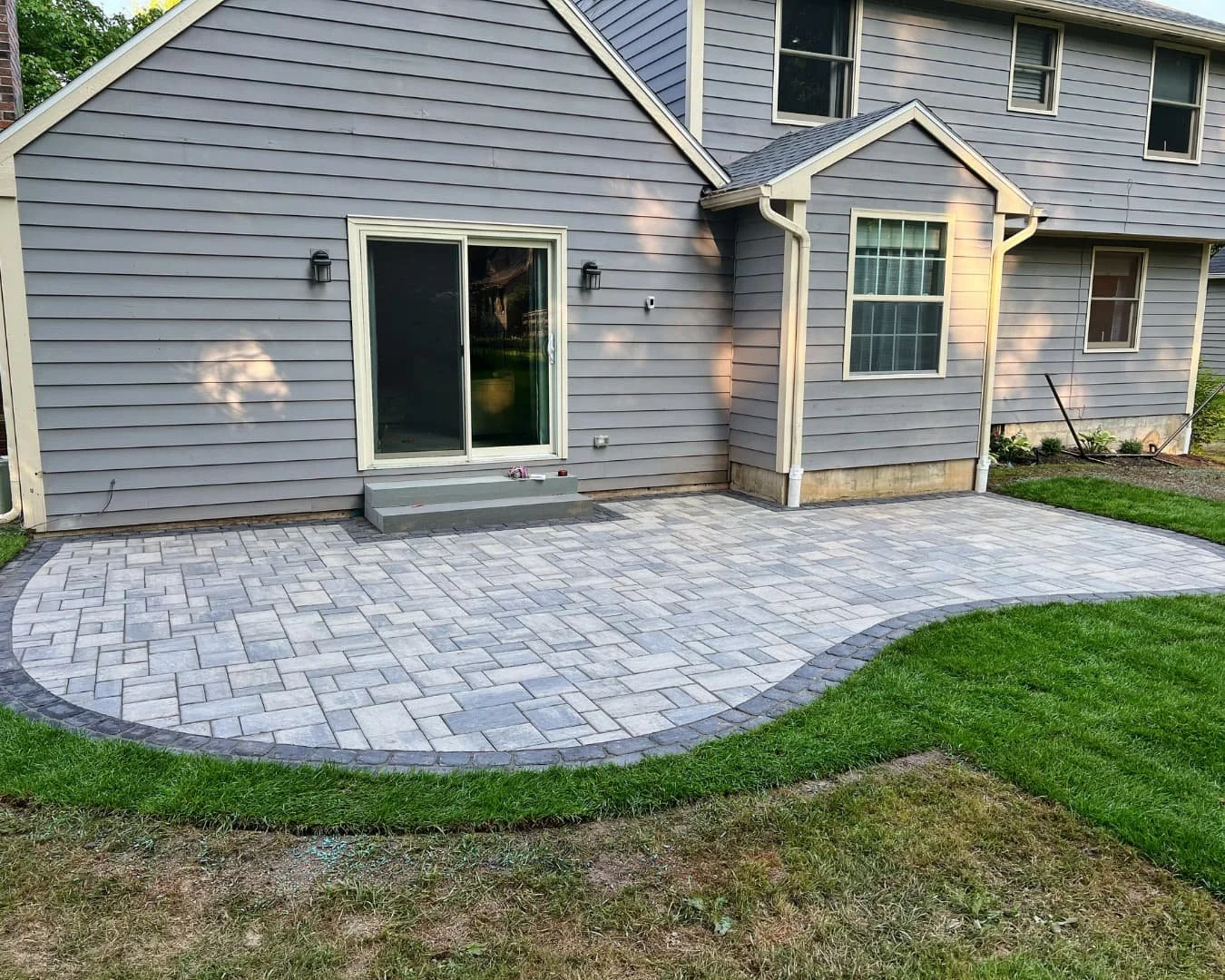 Curved backyard paver patio completed by Pines and Pavers in Baldwinsville, New York.