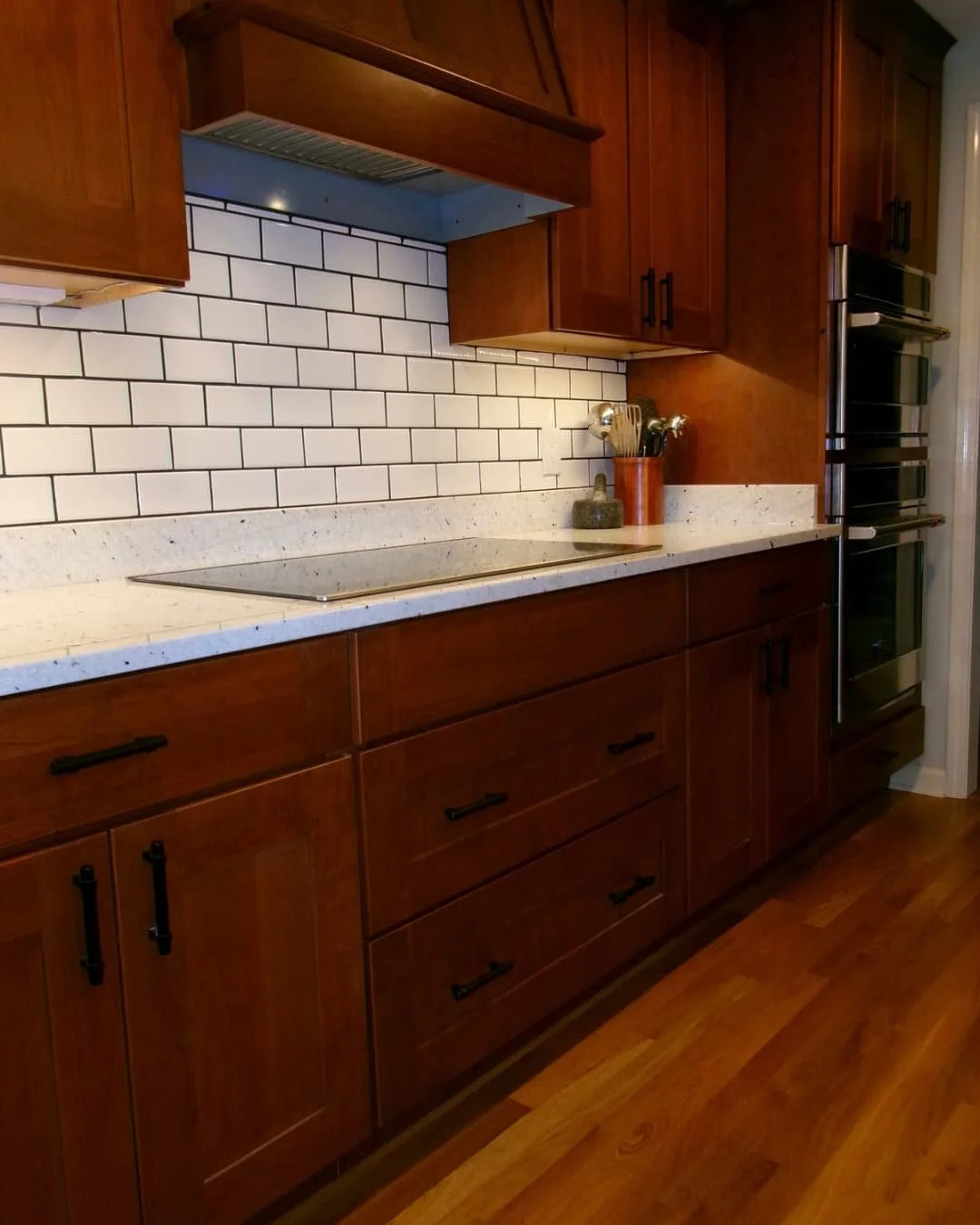 Tile backsplash detail in a Fayetteville, NY kitchen remodel with granite counters and under-cabinet lighting.