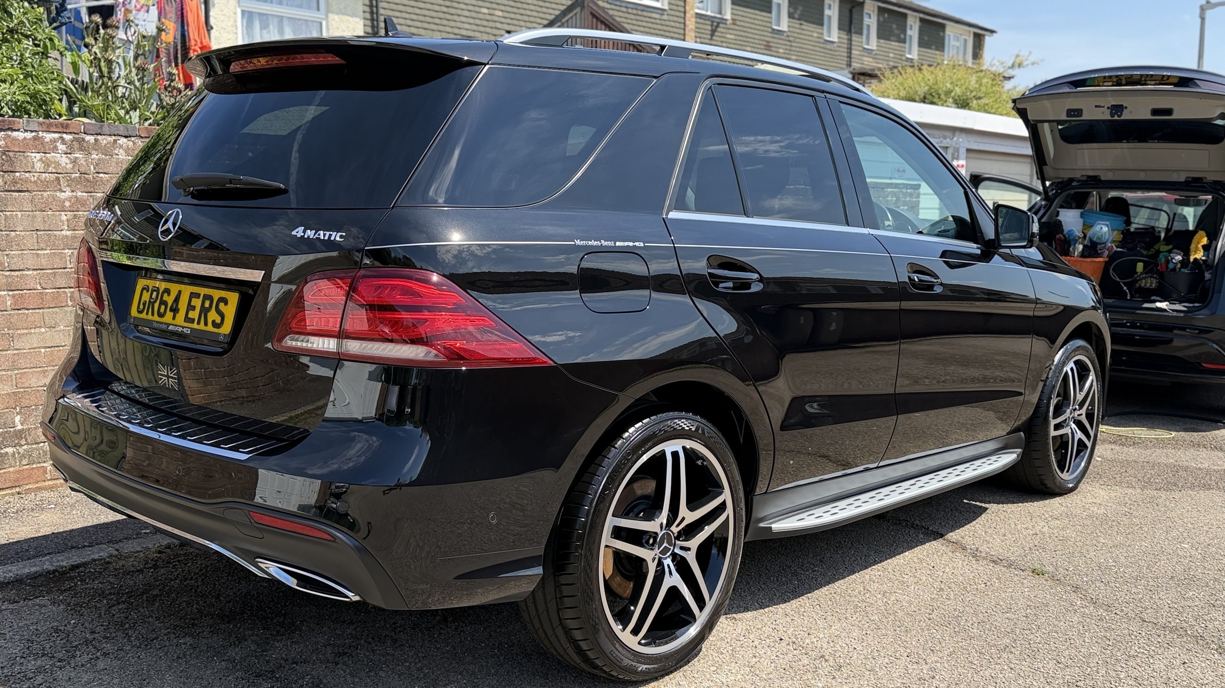 A black Mercedes-Benz EQB SUV parked outside with its rear and side visible. The trunk is open, revealing tools and supplies inside. The car has a yellow license plate with the registration number GRS 4 ERS.