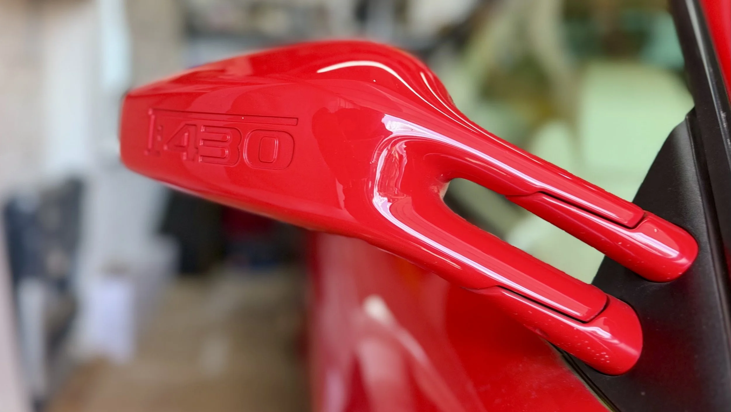 Close-up of a red bicycle saddle with 'Aero' embossed on it, mounted on a black seat post.
