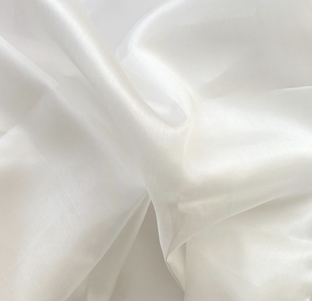 Close-up of smooth, white silk fabric with gentle folds.