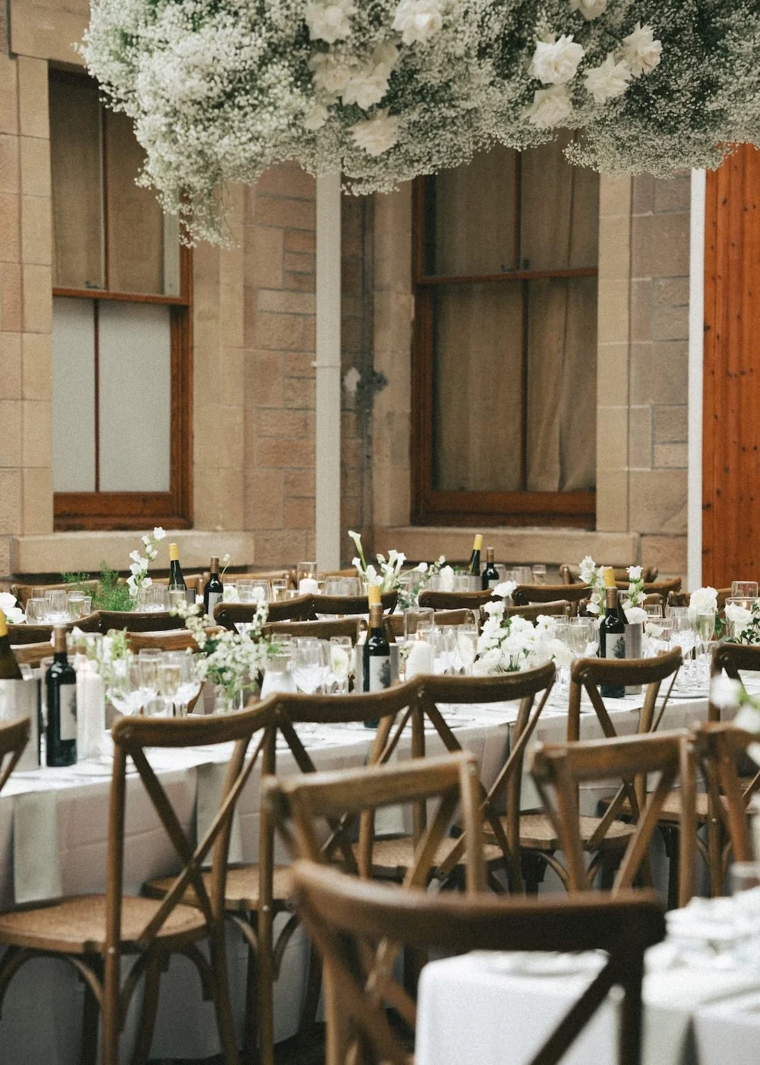 Wedding reception tables decorated with white flowers, wine bottles, and glassware at Rosebery House