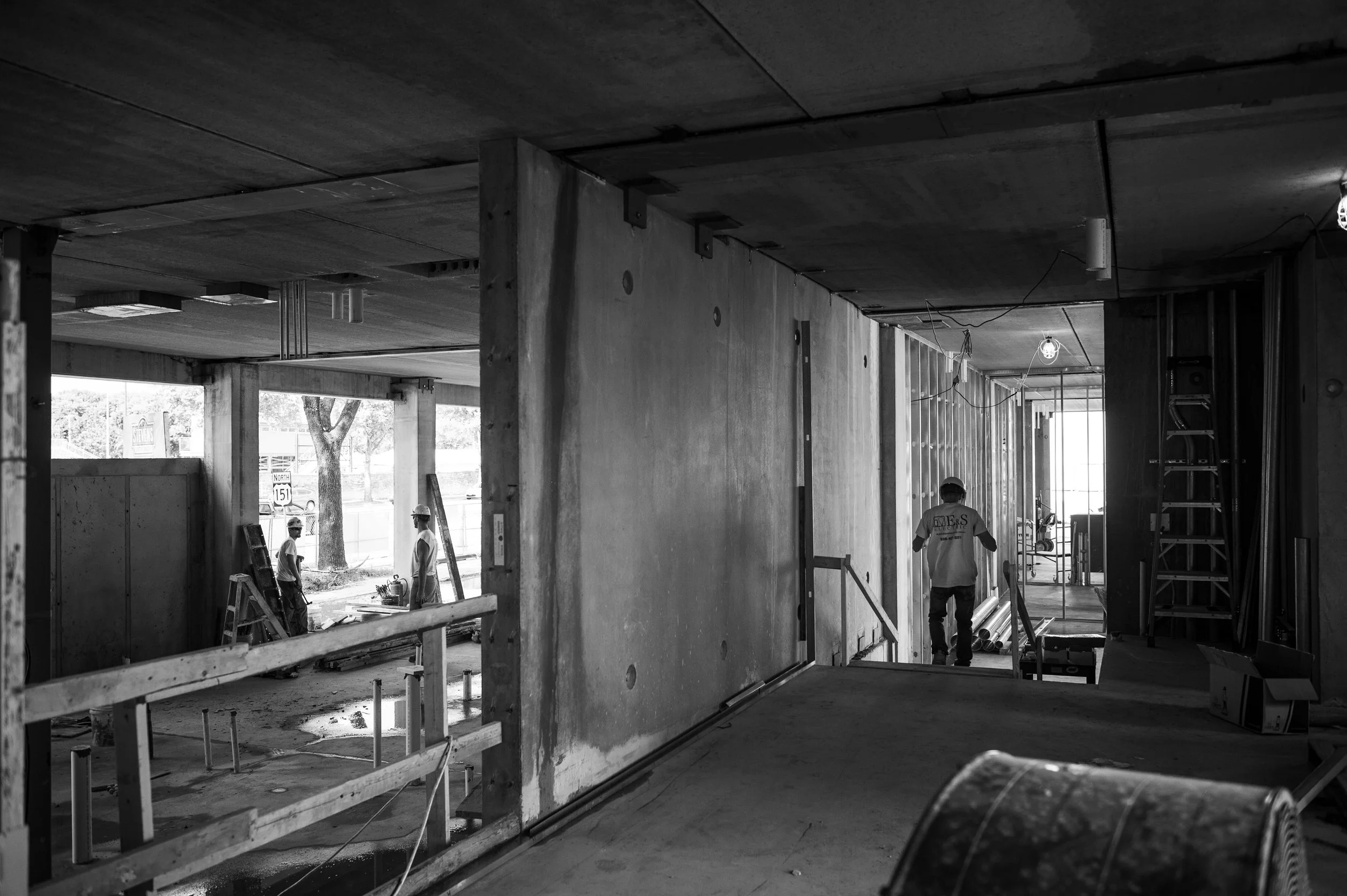 Construction site with workers and building materials inside partially built structure.