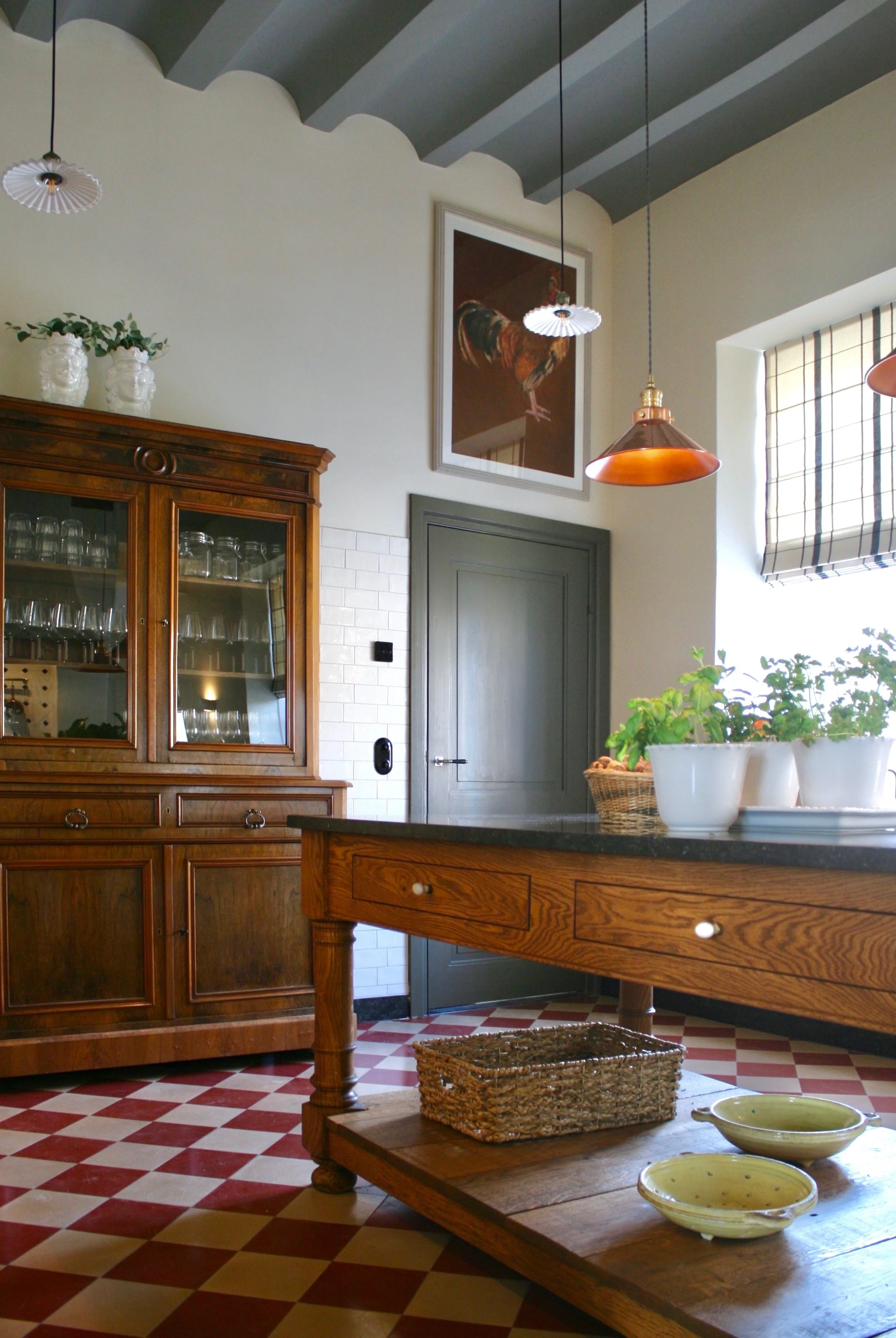 Classic kitchen with red checkerboard floor plaster walls and warm woods copper pendants