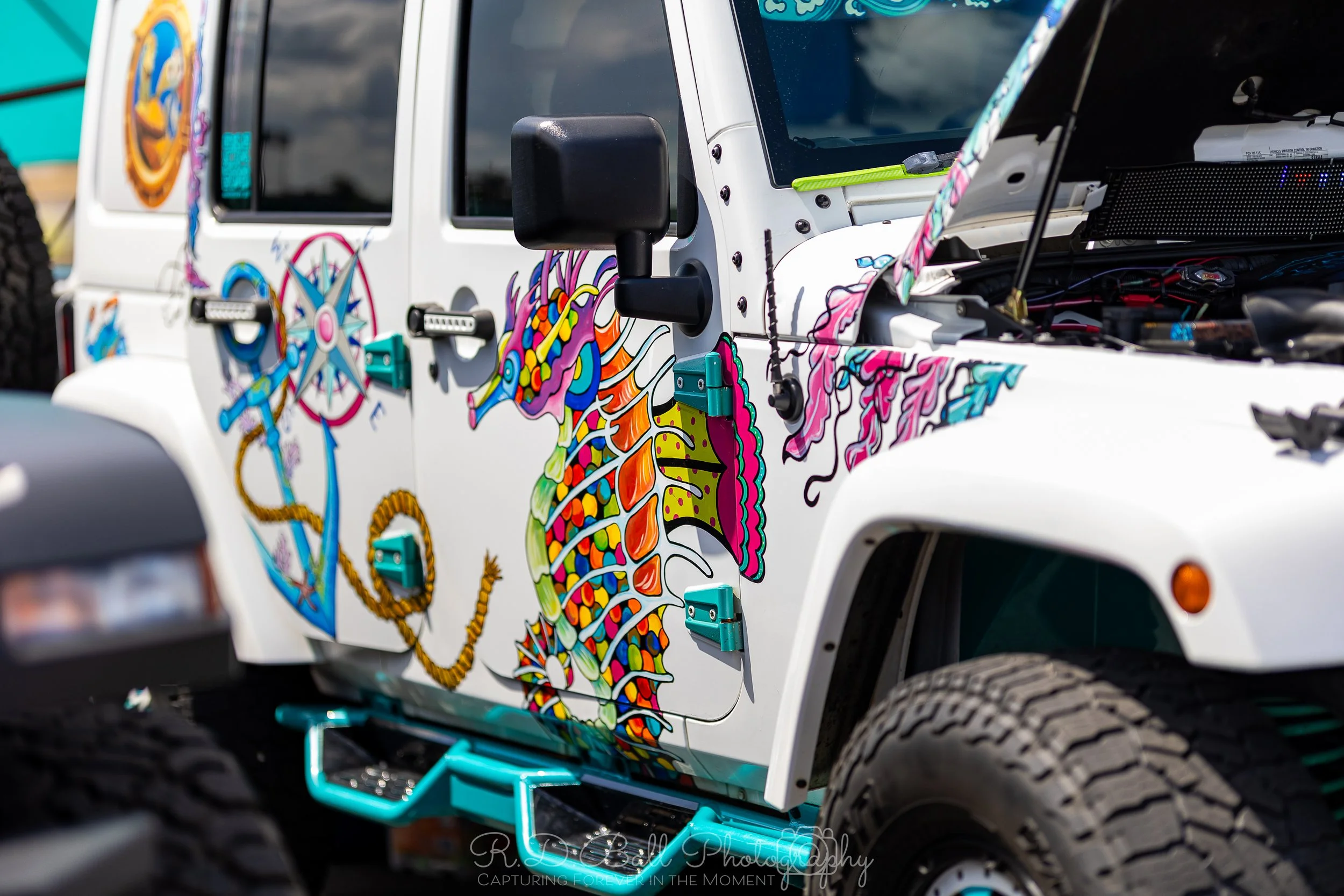 A white off-road vehicle with colorful, artistic dragon and geometric designs painted on its side.