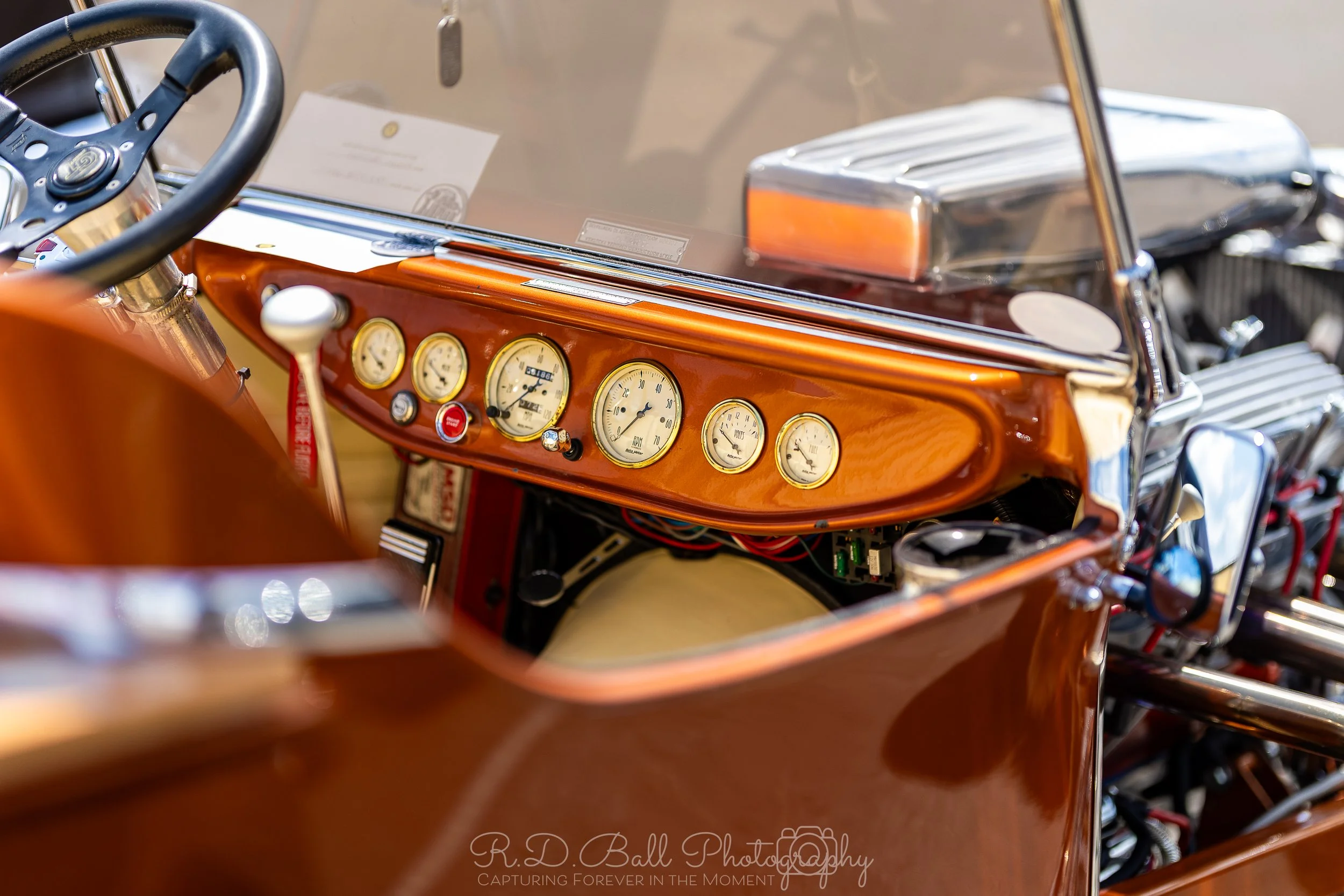 Close-up view of the dashboard of a vintage car with wooden paneling and multiple round gauges.