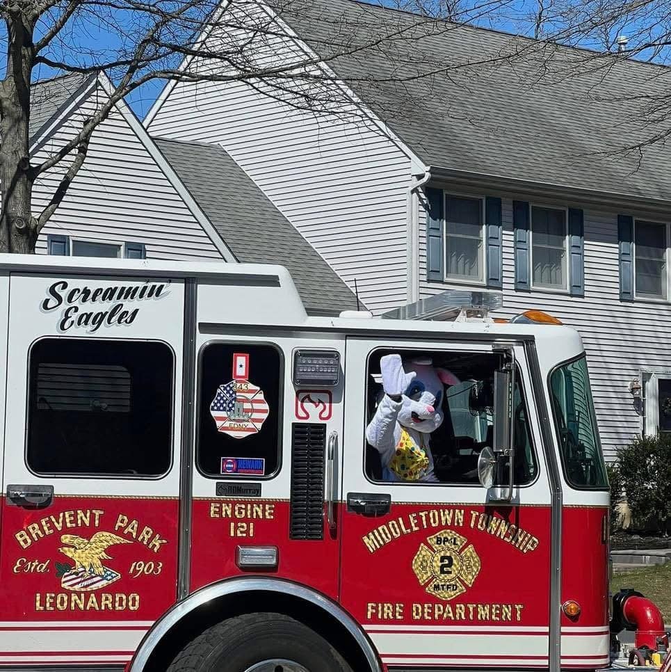 Fire truck with a person in a dog costume waving from the window.