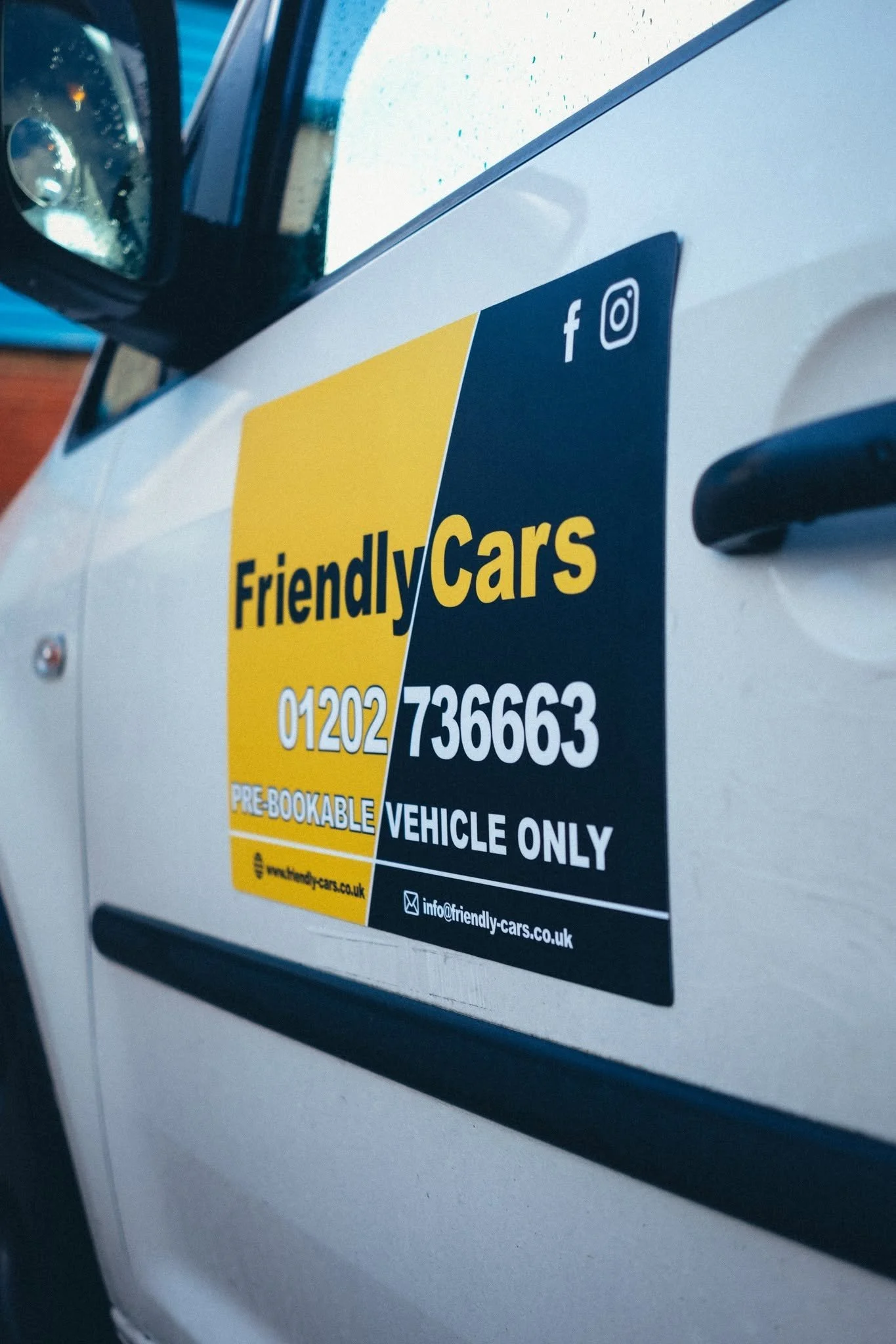 Close-up of a sticker on a vehicle window advertising Friendly Cars, including contact information and social media icons.