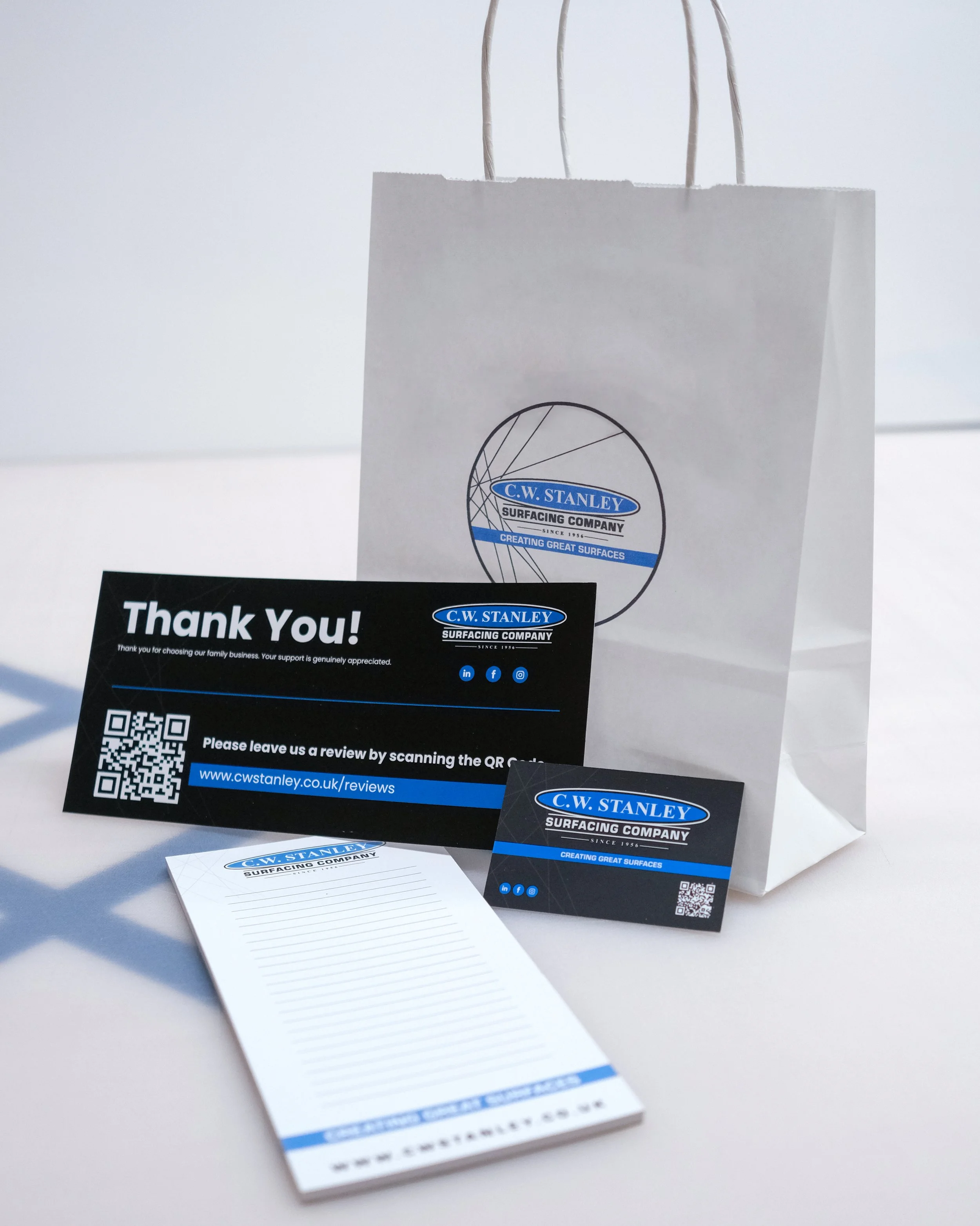 C.W. Stanley Suracing Company branded thank you card, business cards, and notepad with lines, arranged on a white surface, promotional materials for a surfacing company.