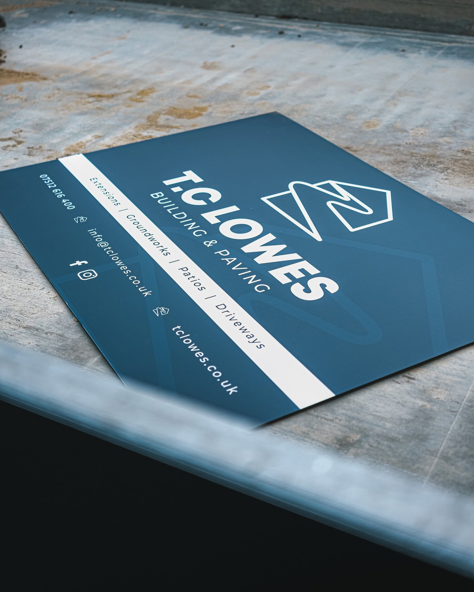 Close-up of a blue business card with white text and logo resting on a wooden surface.