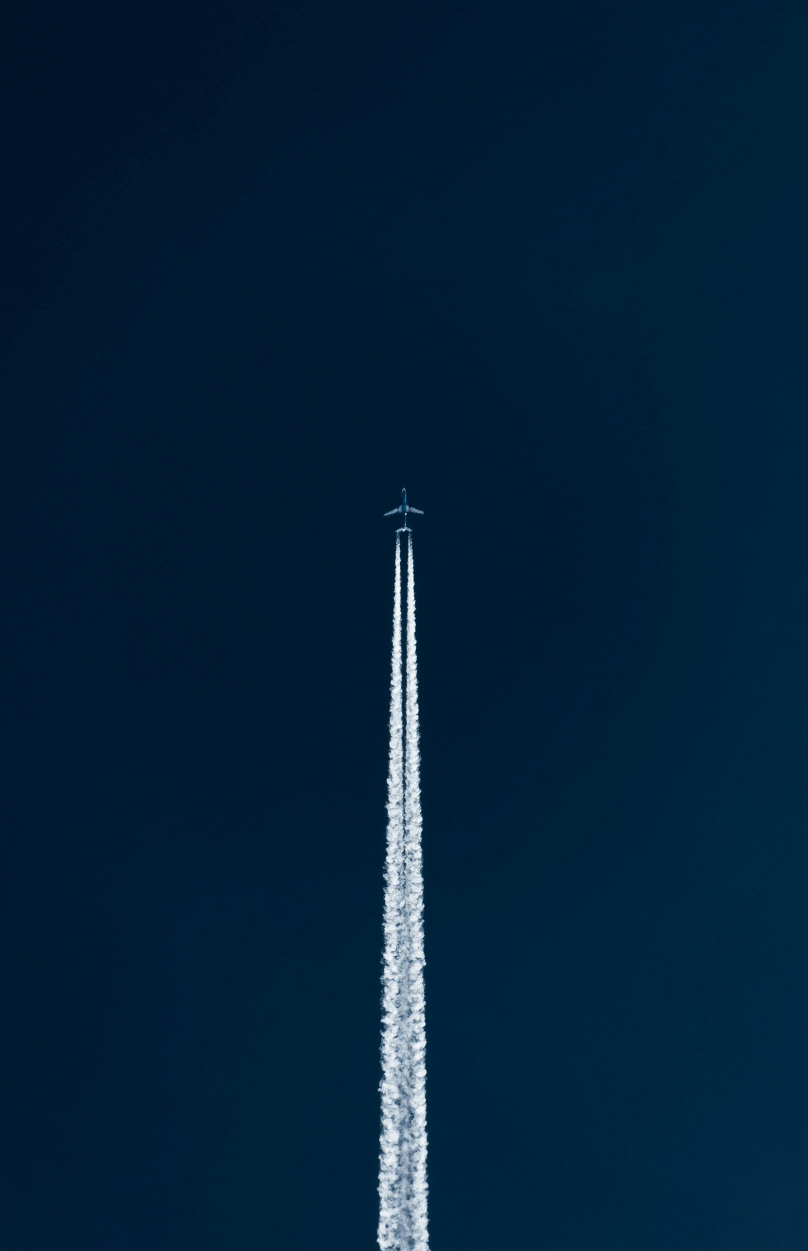 An airplane flying high in the sky, leaving a contrail behind.