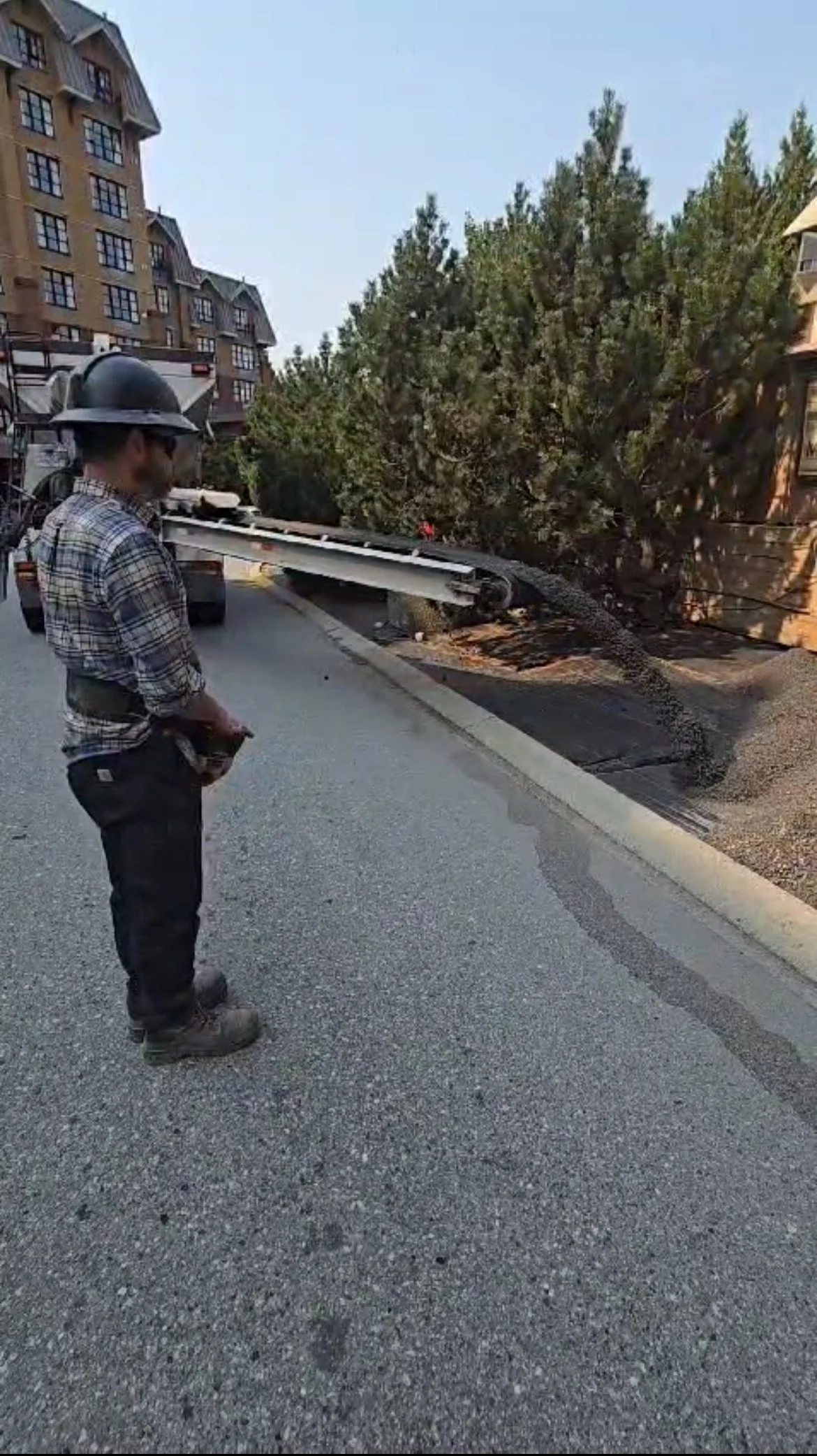 Slinger truck operator precisely placing gravel beside road