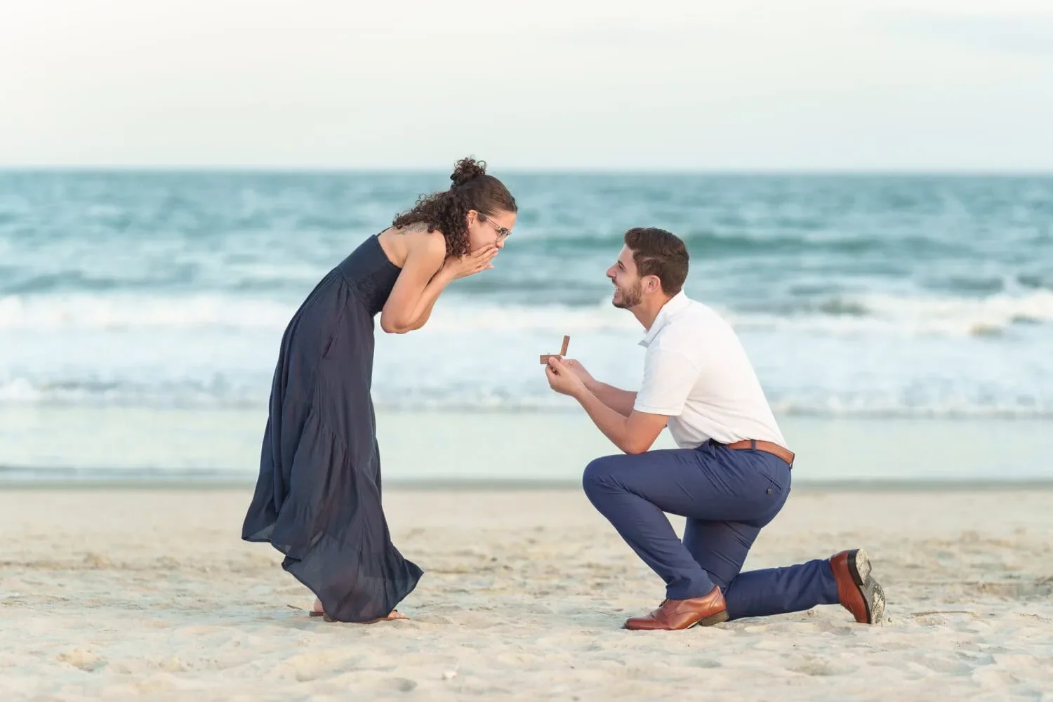 Couple during a beach proposal moment, capturing emotional connection and commitment.