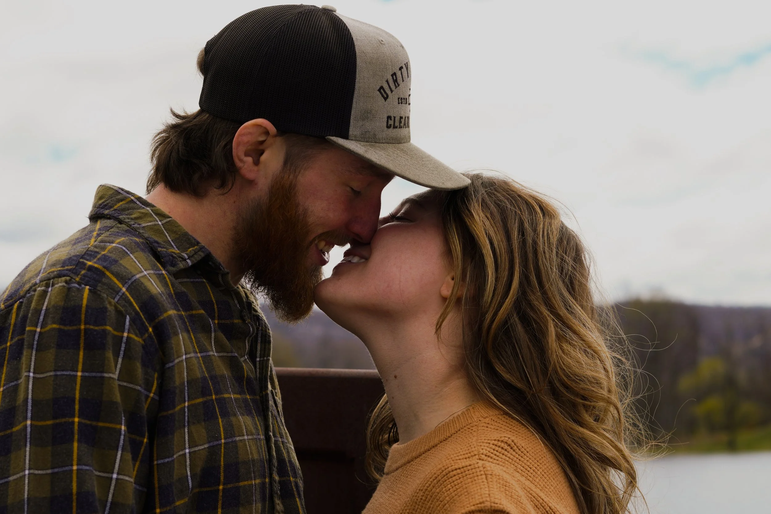 A couple is sharing a close moment outdoors, touching their foreheads and noses together, smiling with eyes closed. Cheap photographer northern nj