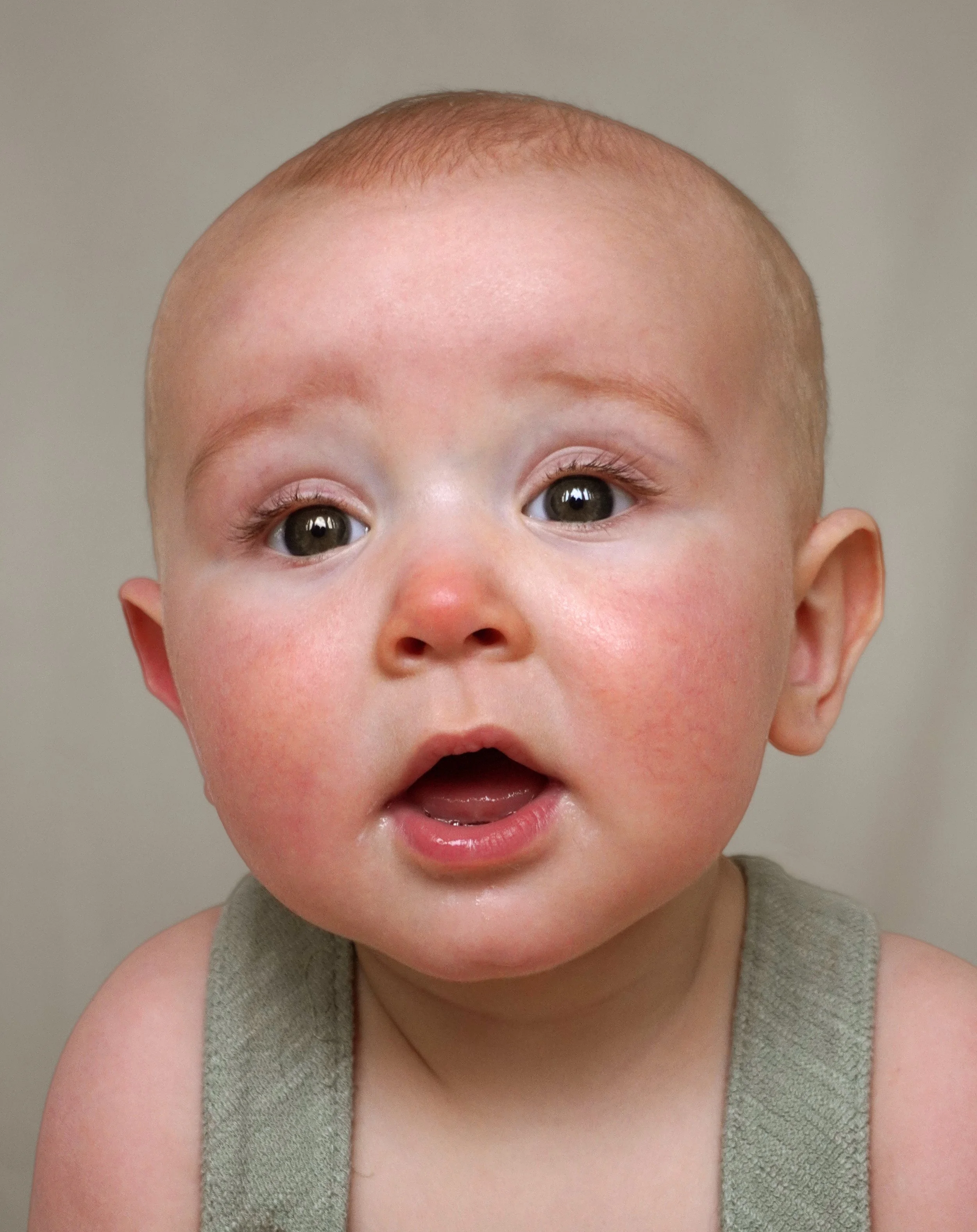 Close-up of a young child's face with surprised expression, wearing a sleeveless top. Baby photographer northern nj
