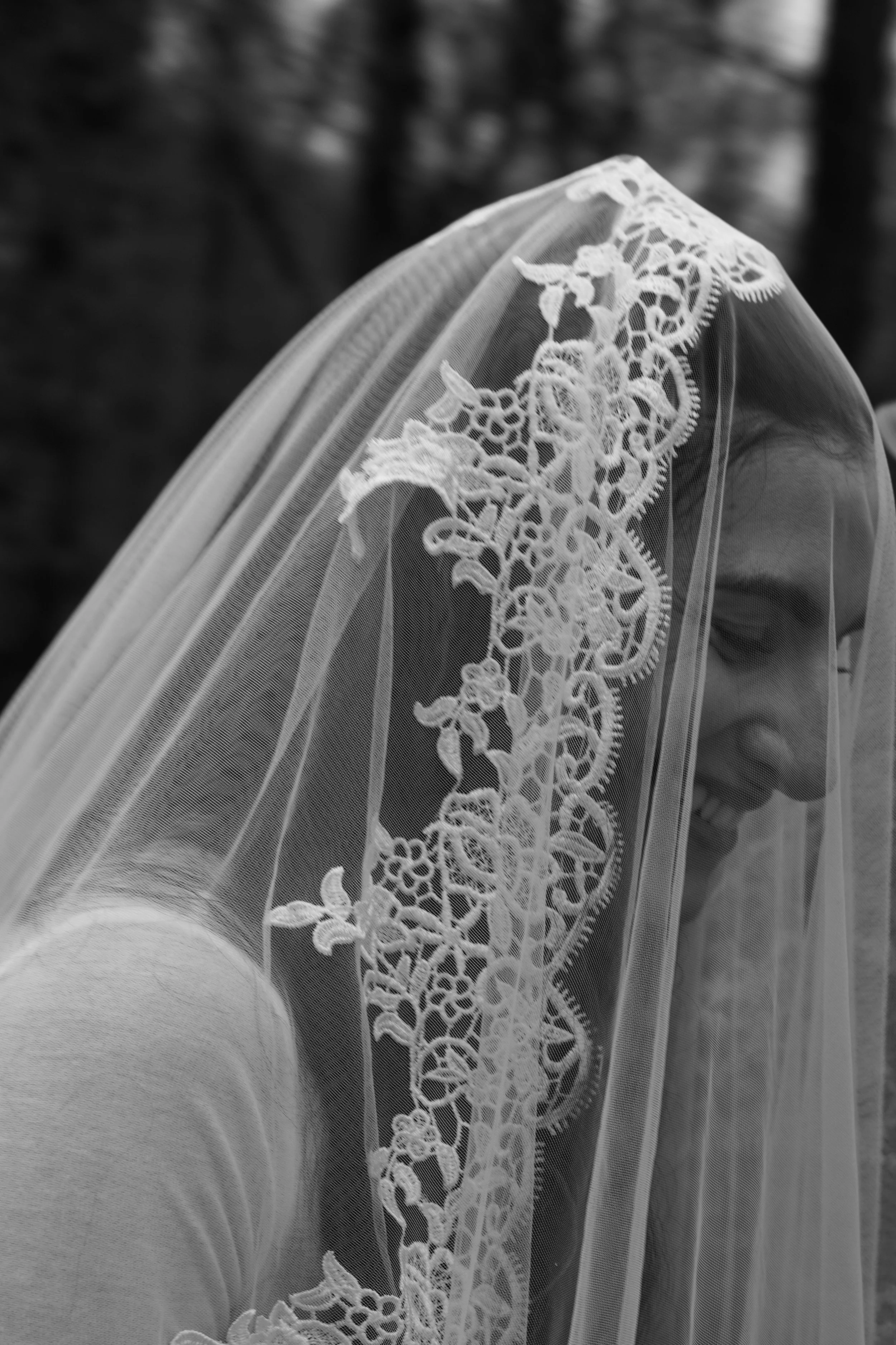 A woman wearing a lace wedding veil, smiling with her eyes closed. Wedding photographer