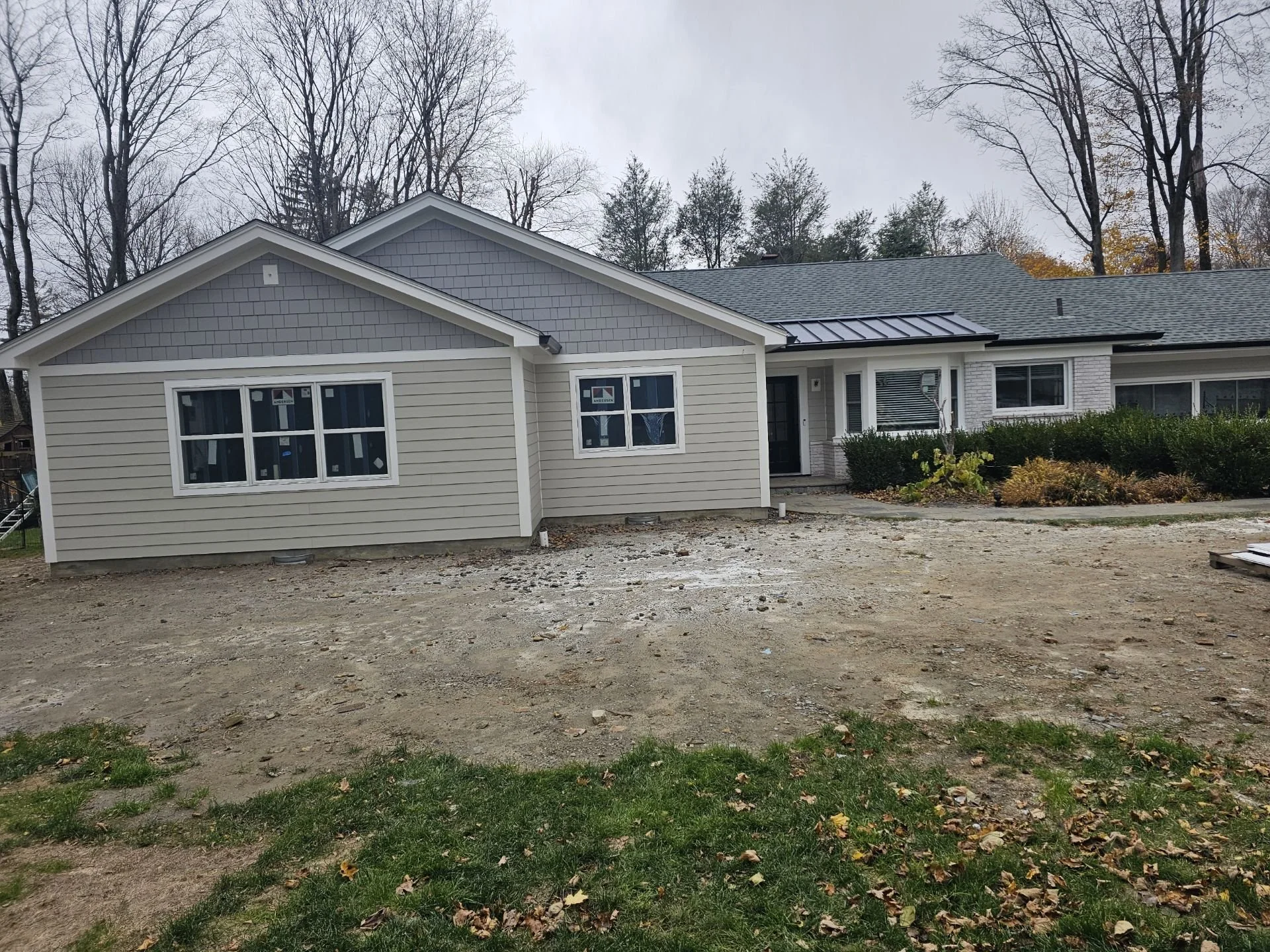 Front view of a house under construction with a partially completed driveway and landscaping.