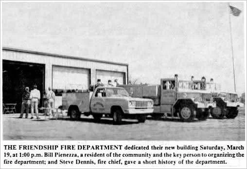A black-and-white photo of a group of people and vehicles in front of a fire department building, with a caption about the dedication of a new fire department building.