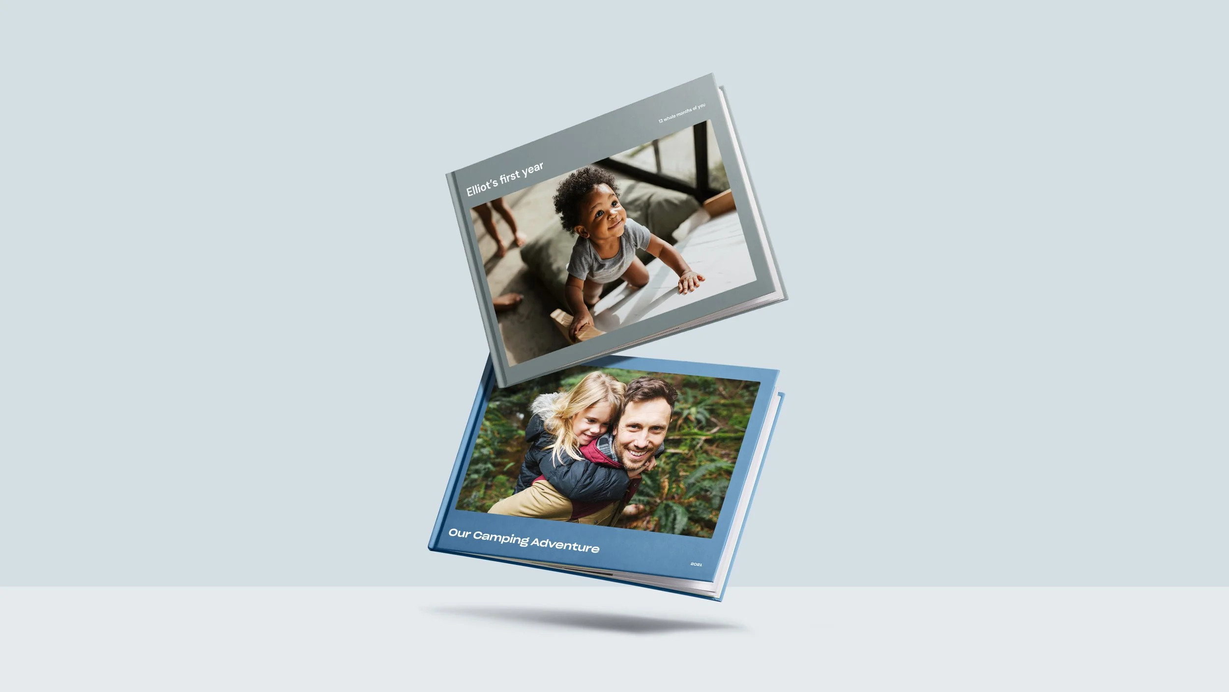 Open photo books, one with a toddler climbing onto a bed and another with a man and a young girl outdoors in a wooded area.