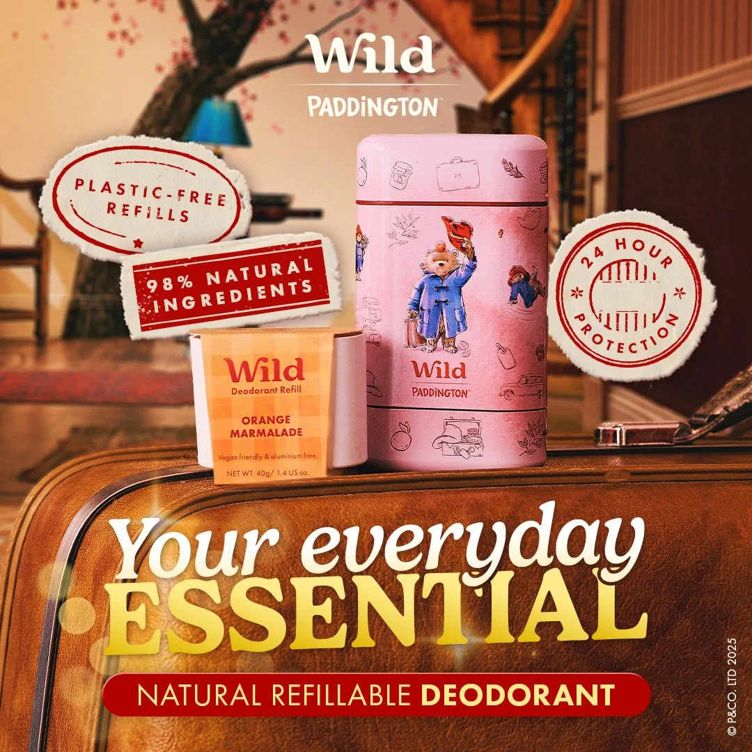 A pink tins of Wild Paddington deodorant, a small box of Wild deodorant refill orange marmalade, and promotional text on a background featuring a bedroom with a tree and wall art. The text highlights features like plastic-free refills, 98% natural ingredients, and 24-hour protection.