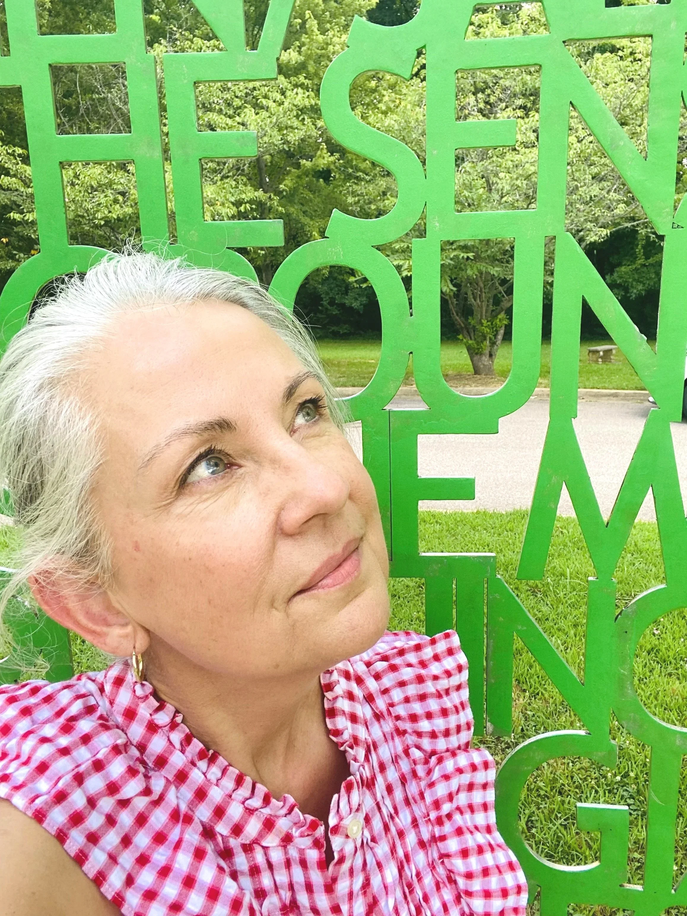 middle aged woman surrounded by a word sculpture