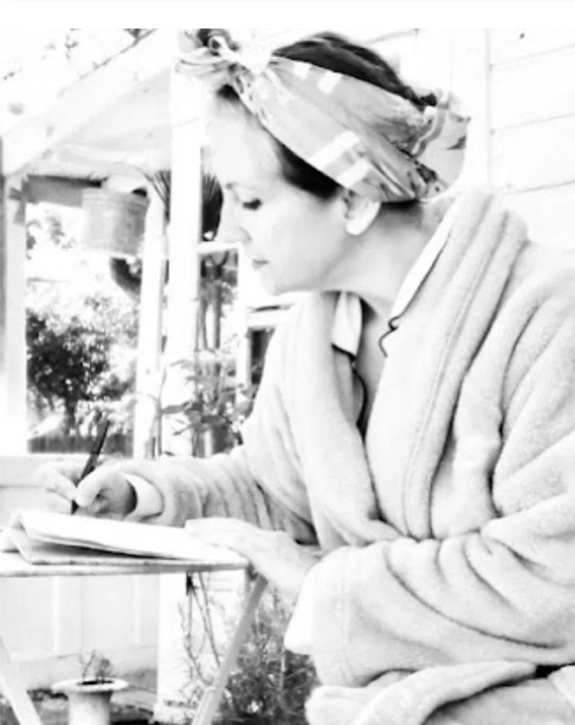 woman writing a letter in her garden wearing a robe