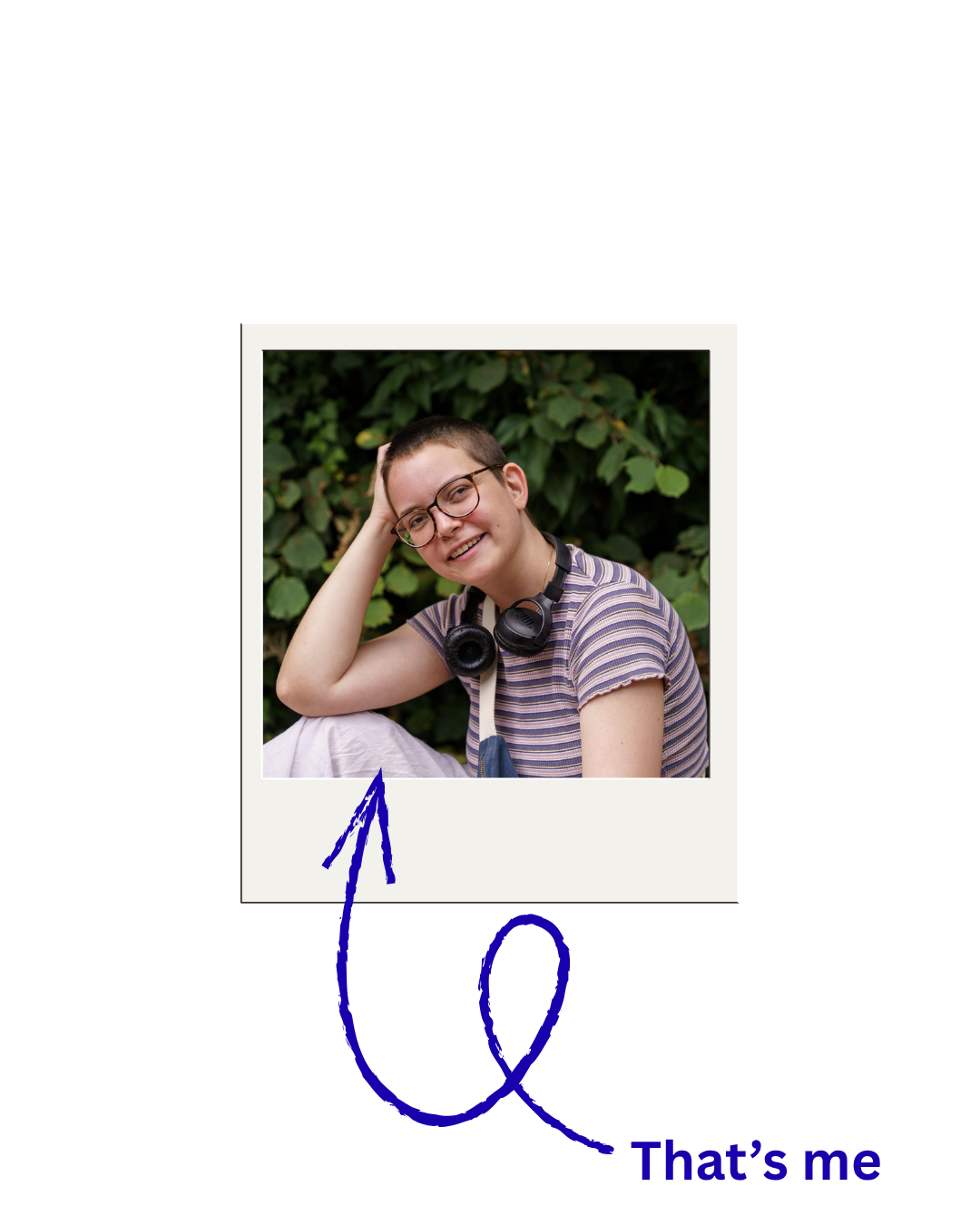 Eine junge Frau (Emily Gündling) mit Brille, kurze Haare, trägt ein gestreiftes T-Shirt und Kopfhörer um den Hals, lächelt und lehnt den Kopf auf die Hand, im Hintergrund grüne Blätter.