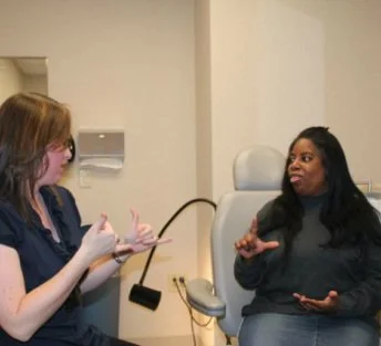 Two women in a doctors office using sign language.