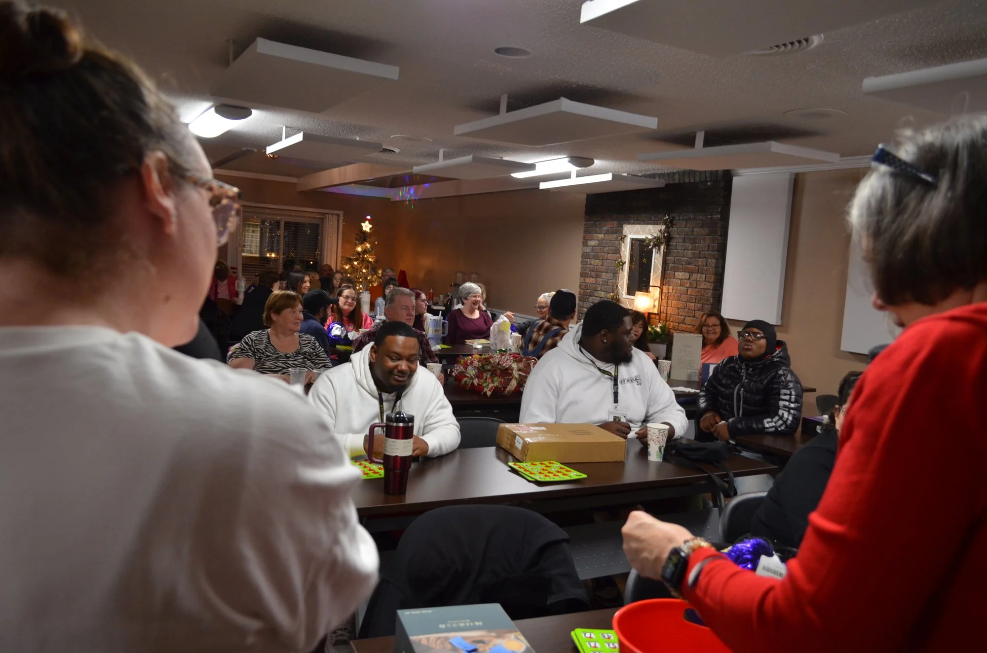 A group of around 25 people smiling, playing bingo, and winning prizes at the JCIL Christmas party.