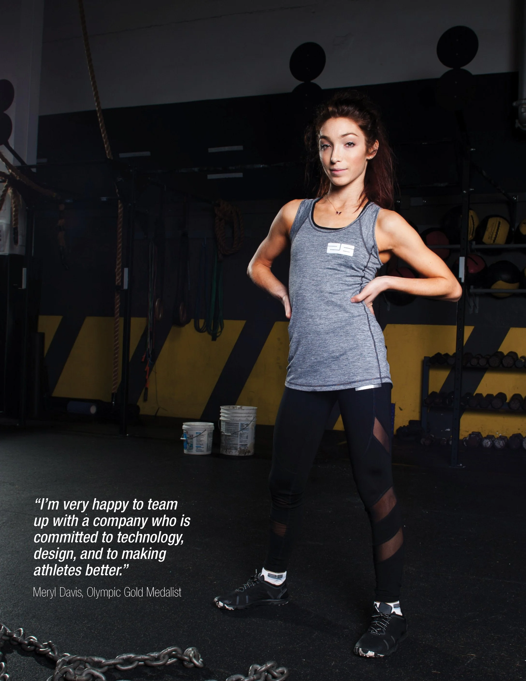 A woman in athletic clothing stands in a gym, with her hands on her hips, looking confident. The gym has black flooring, yellow and black walls, and various exercise equipment in the background. There are quote text at the bottom left that says: 'I'm very happy to team up with a company who is committed to technology, design, and to making athletes better.' - Meryl Davis, Olympic Gold Medalist.