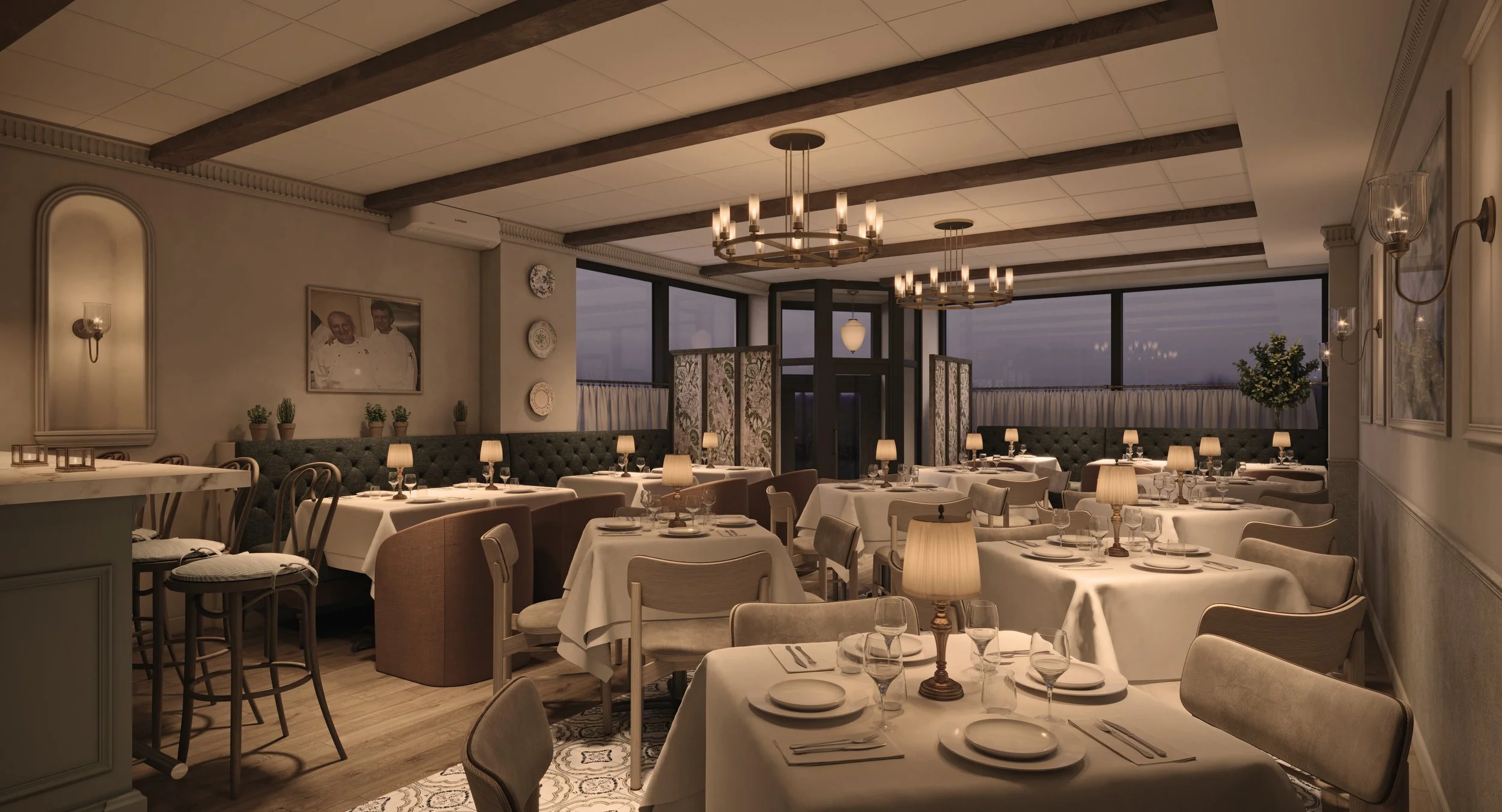 Elegant restaurant dining room with white tablecloths and beige chairs, chandeliers hanging from ceiling, large windows with curtains, and framed photos on wall.