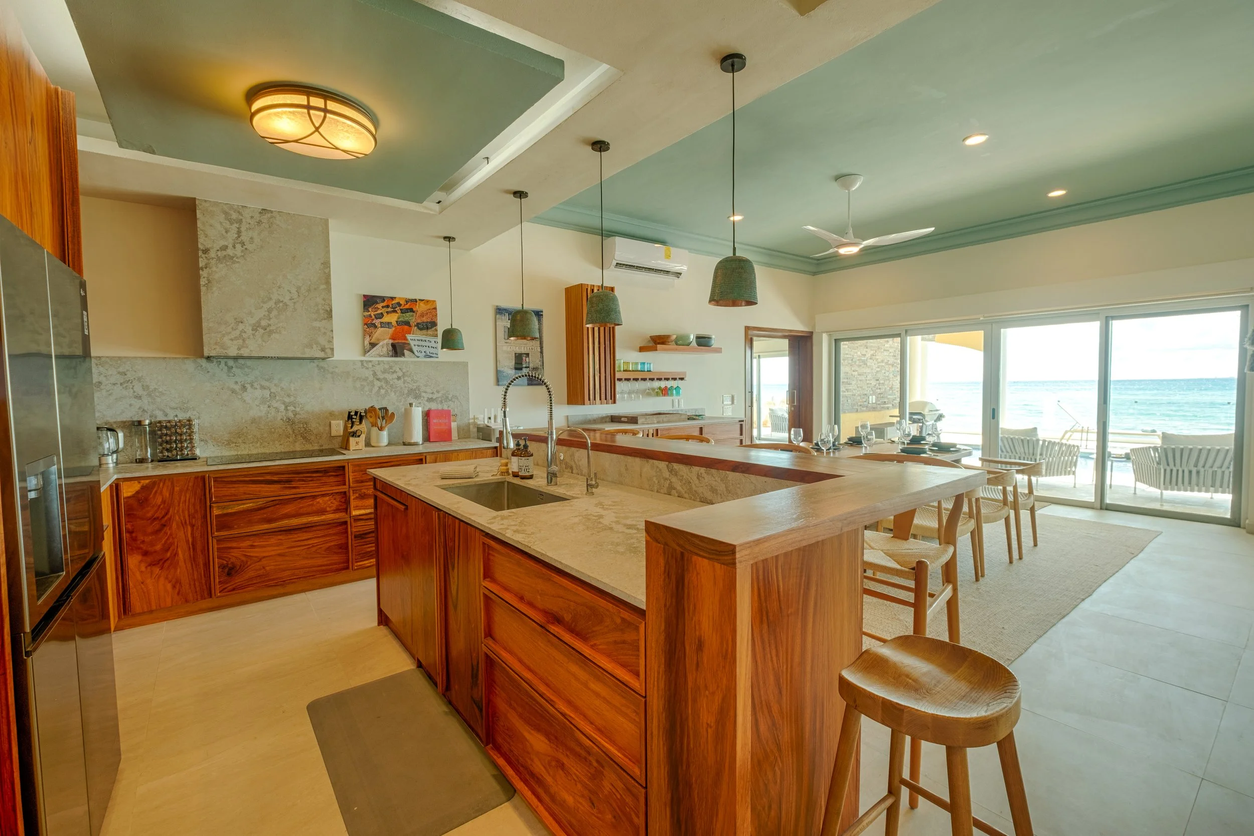 Open-concept kitchen and dining area with wooden cabinets and a view of the ocean through sliding glass doors
