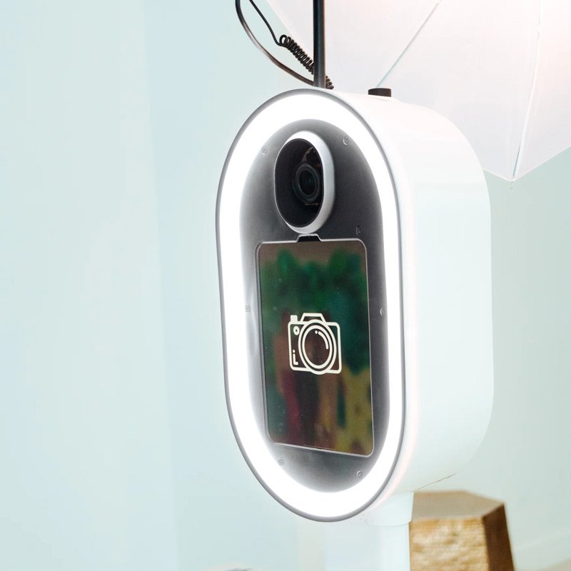 A glowing oval photo booth with a built-in ring light and camera, ready to capture every guest in their best light, the kind of fun, elevated keepsake experience Palm Events & Rentals brings to weddings and events.