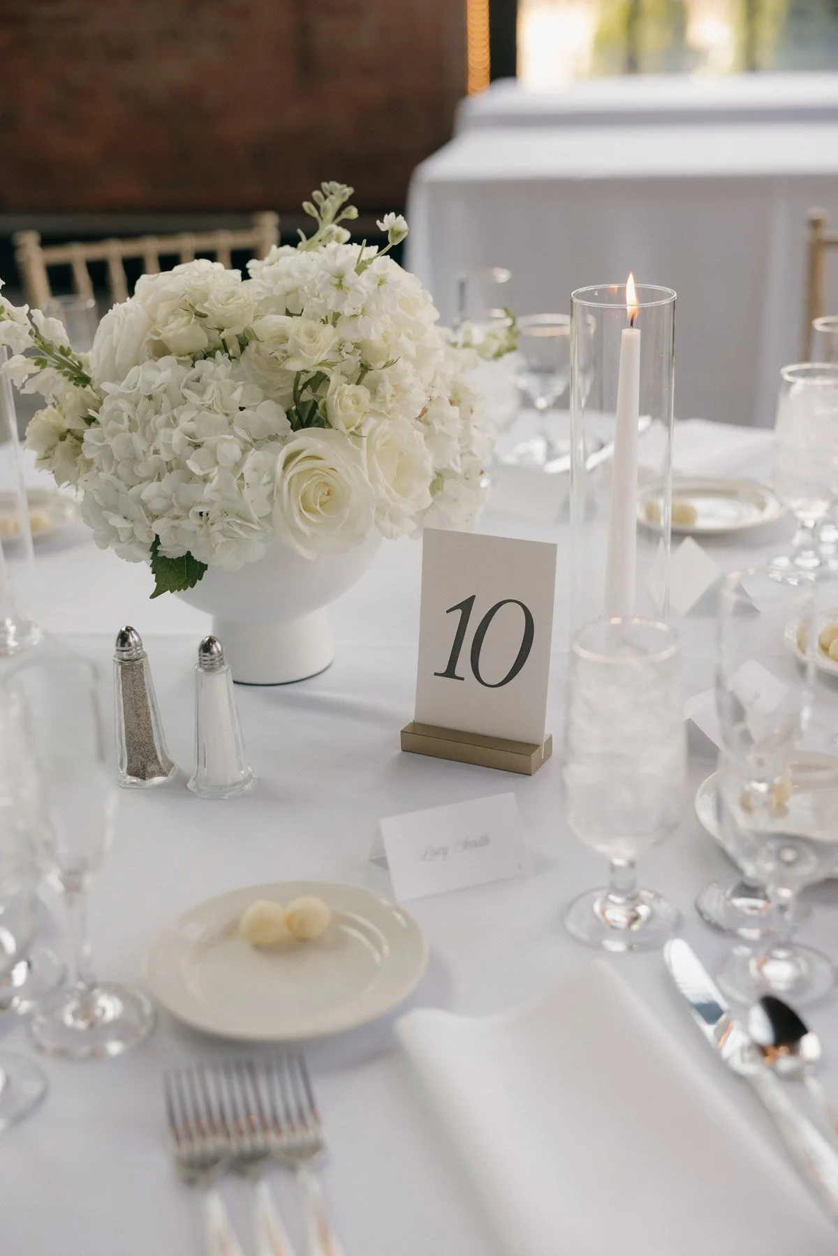 A lush all-white wedding tablescape with a floral centerpiece, glowing candles, and polished glassware, brought to life by Palm Events & Rentals full-service event design and fulfillment.