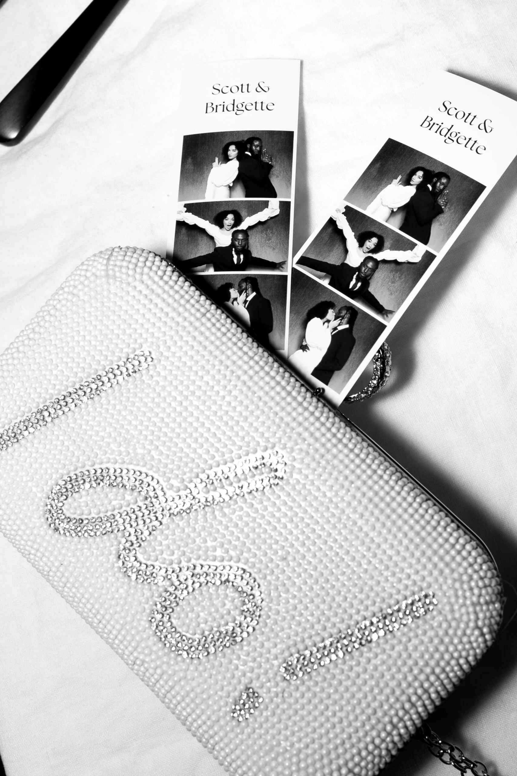 A rhinestone clutch beside two photo booth strips capturing a couple's sweetest moments, the kind of tangible keepsake guests take home when Palm Events & Rentals brings a photo booth to your wedding or event.