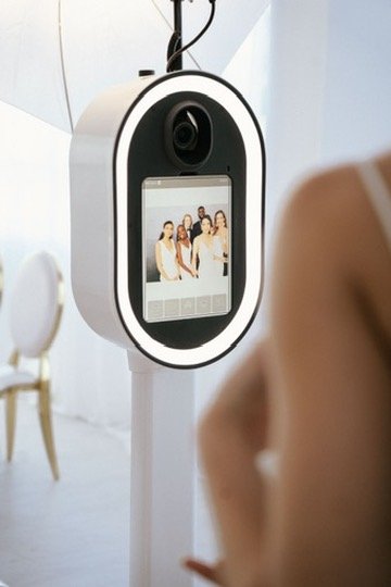 A modern photo booth display showing a group of friends captured mid-celebration, the kind of fun keepsake moment Palm Events & Rentals photo booth rentals bring to weddings and events.