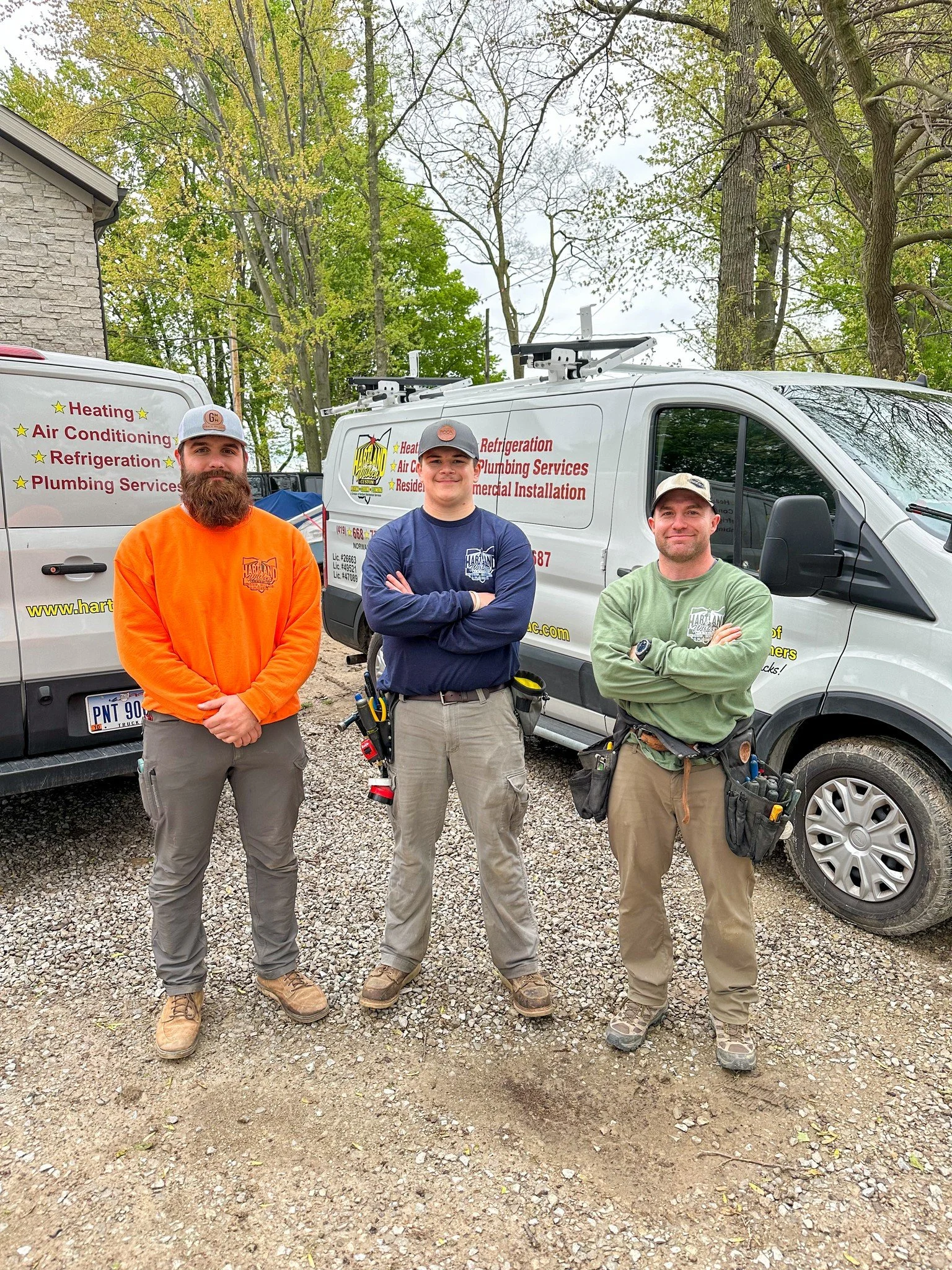 Hartland & Wilken Custom Heating, Cooling, Plumbing, Electric crew stands outside next to their service trucks.