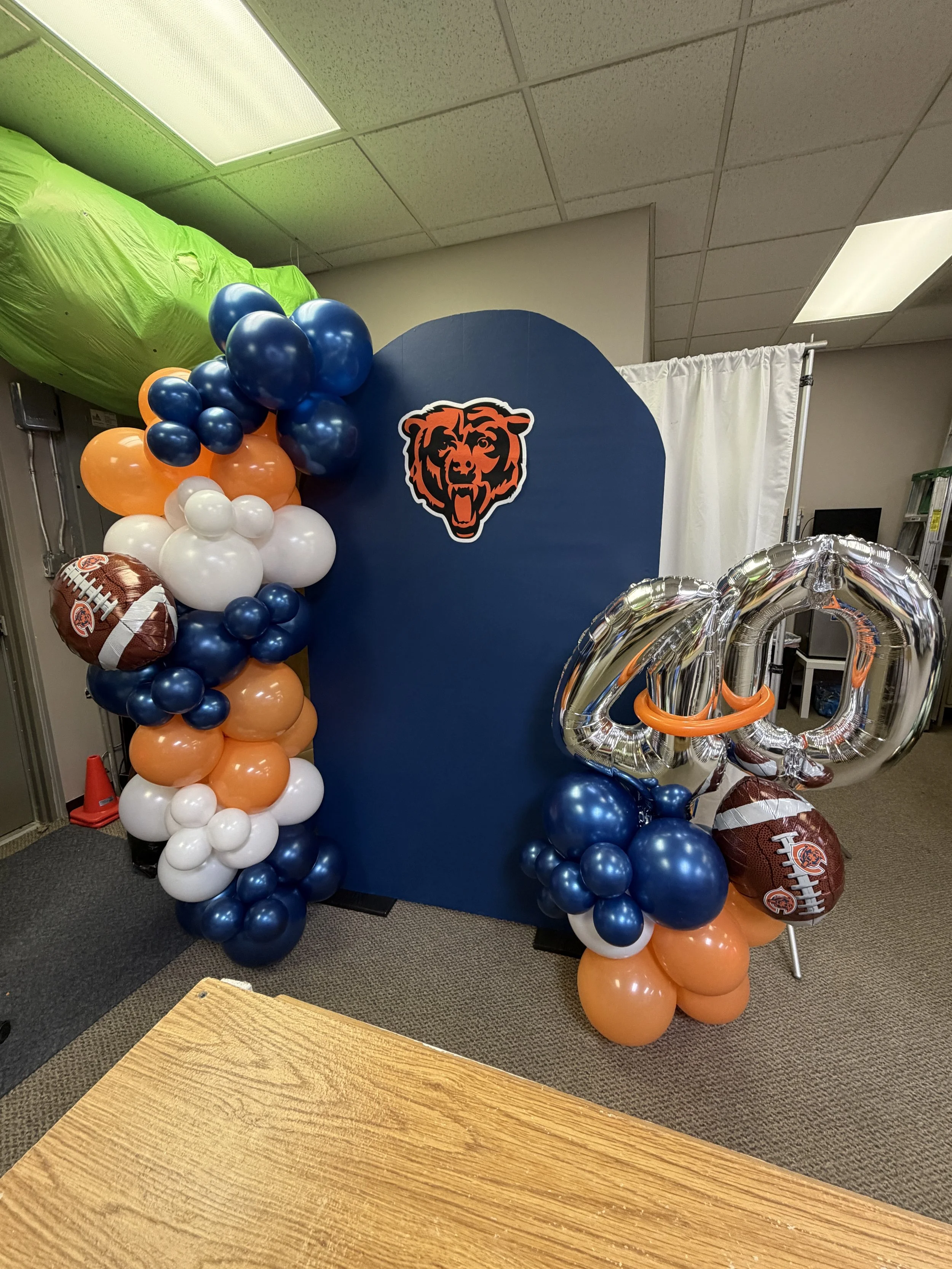 Decorative display with a Chicago Bears logo, blue, orange, white, and navy balloons, football-shaped balloons, and a large silver number 40 balloon.