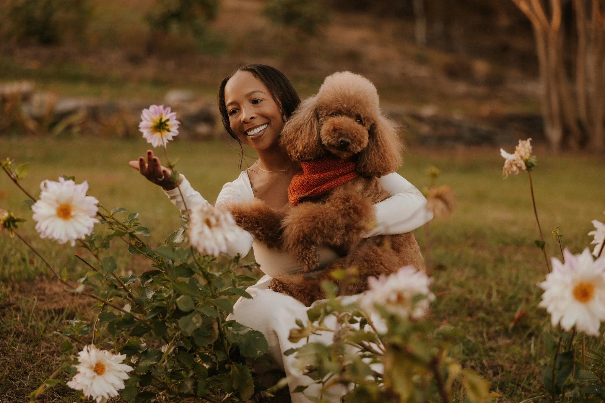 Girl holding dog in a field of flowers.