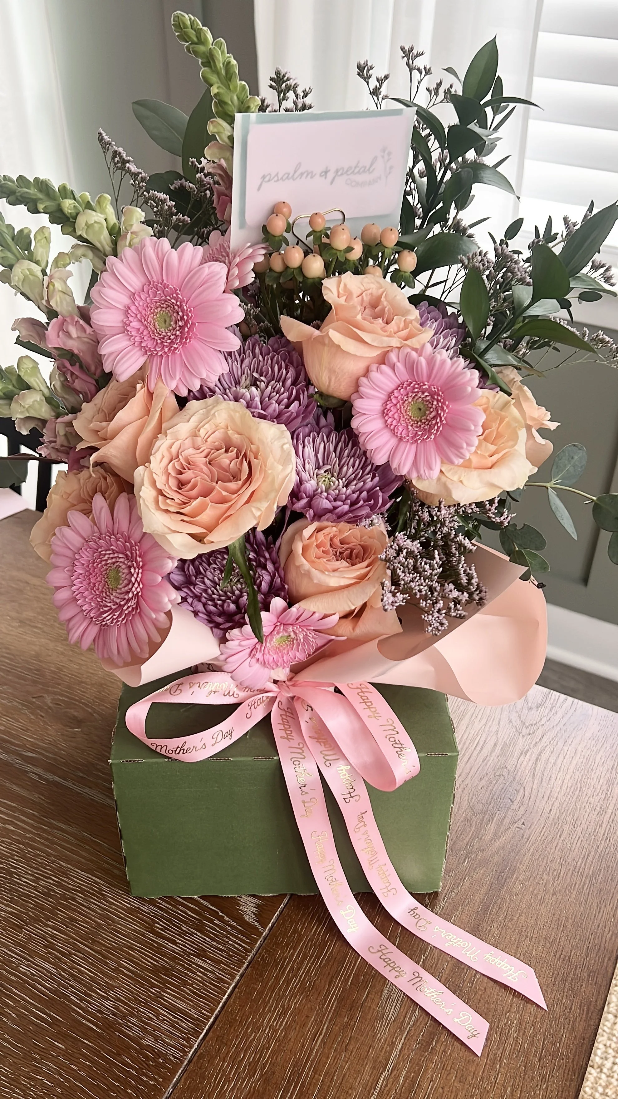 Elevated floral bouquet with assorted coral, pink and cream flowers delicately tied with a pink satin ribbon