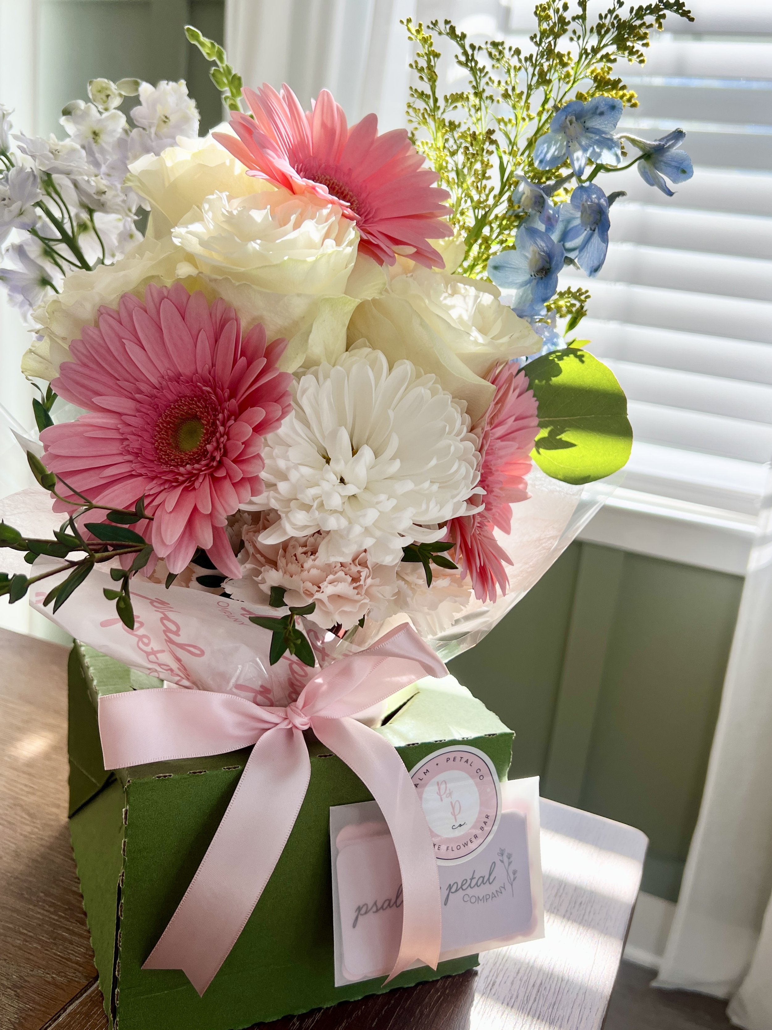 Hand-wrapped bouquet with light pink roses, spray roses, and lavender accent petals