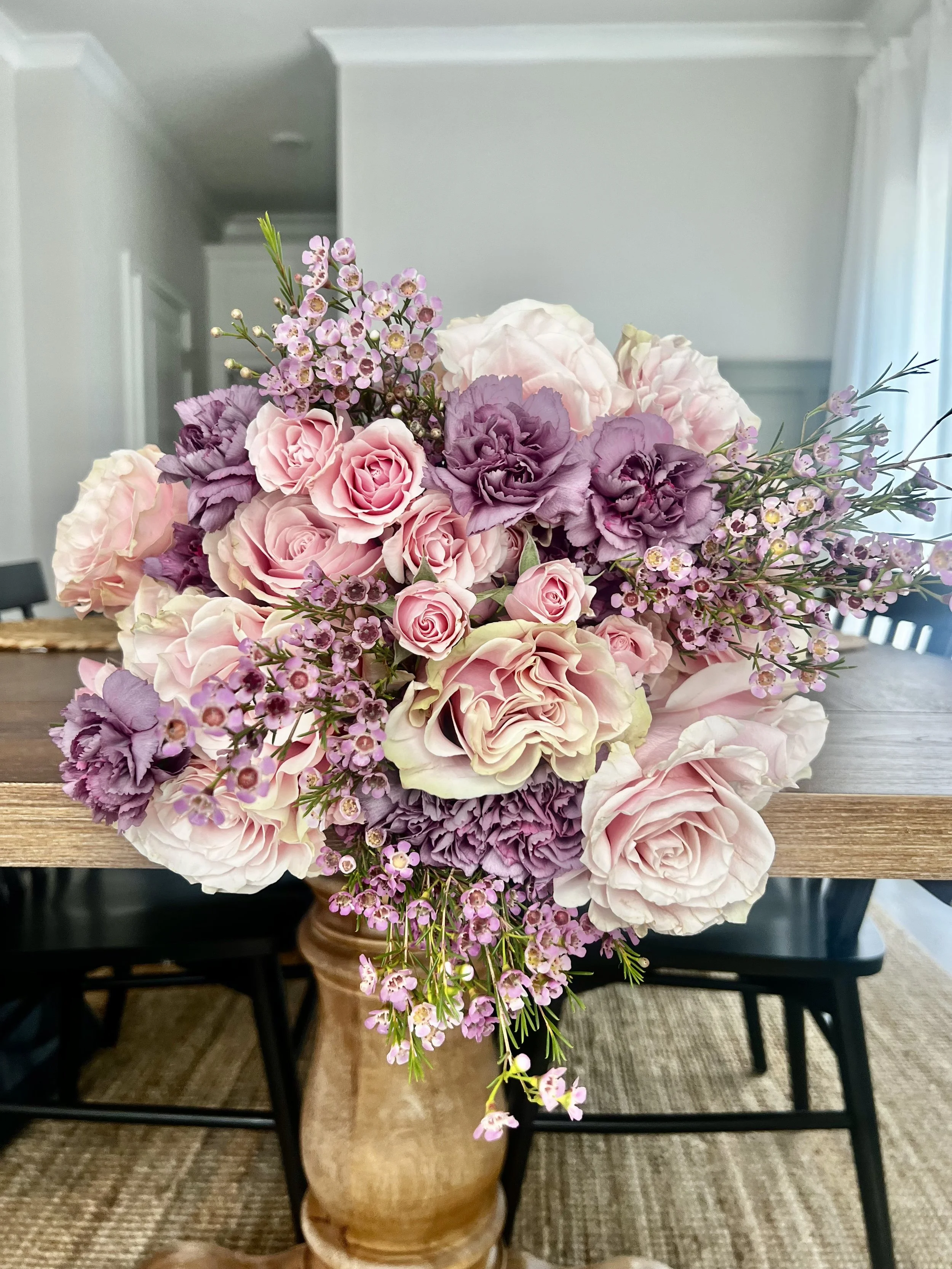 Hand-wrapped bouquet with light pink roses, spray roses, and lavender accent petals