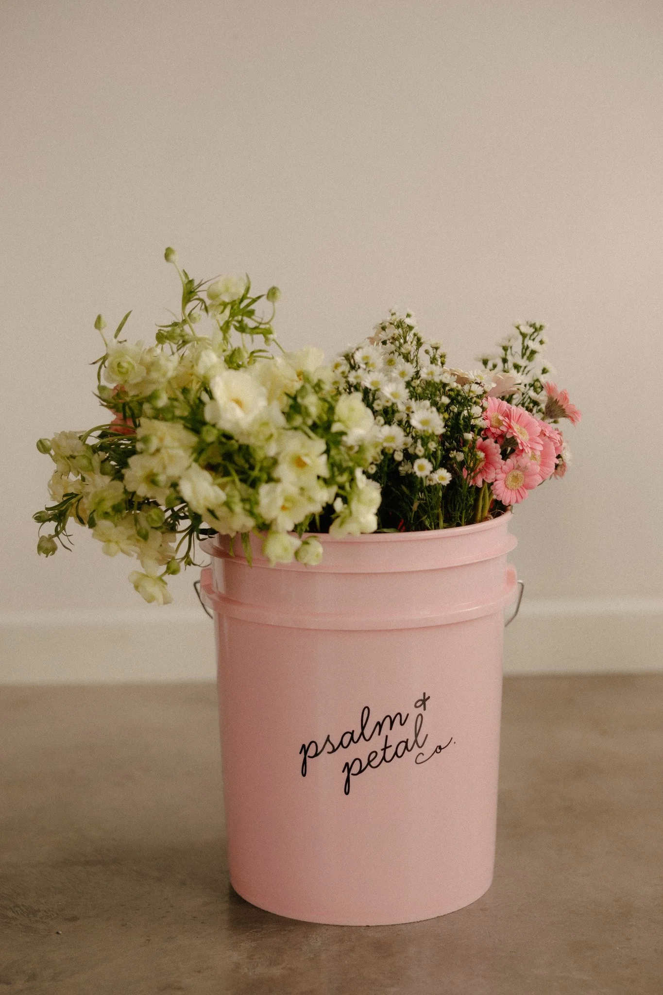 Pink P+P Co. branded flower bucket with various flowers sticking out