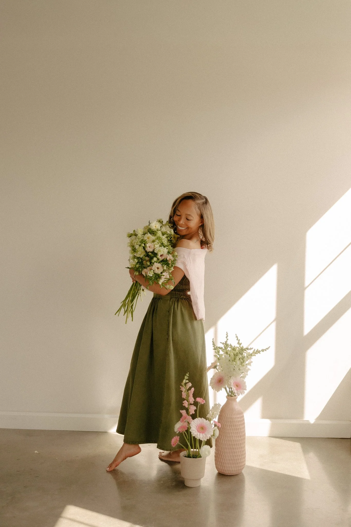 Girl in green dress standing on toes holding white bouquet of flowers.