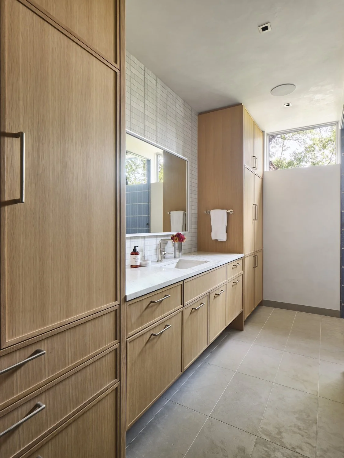 primary bathroom with light wood cabinets