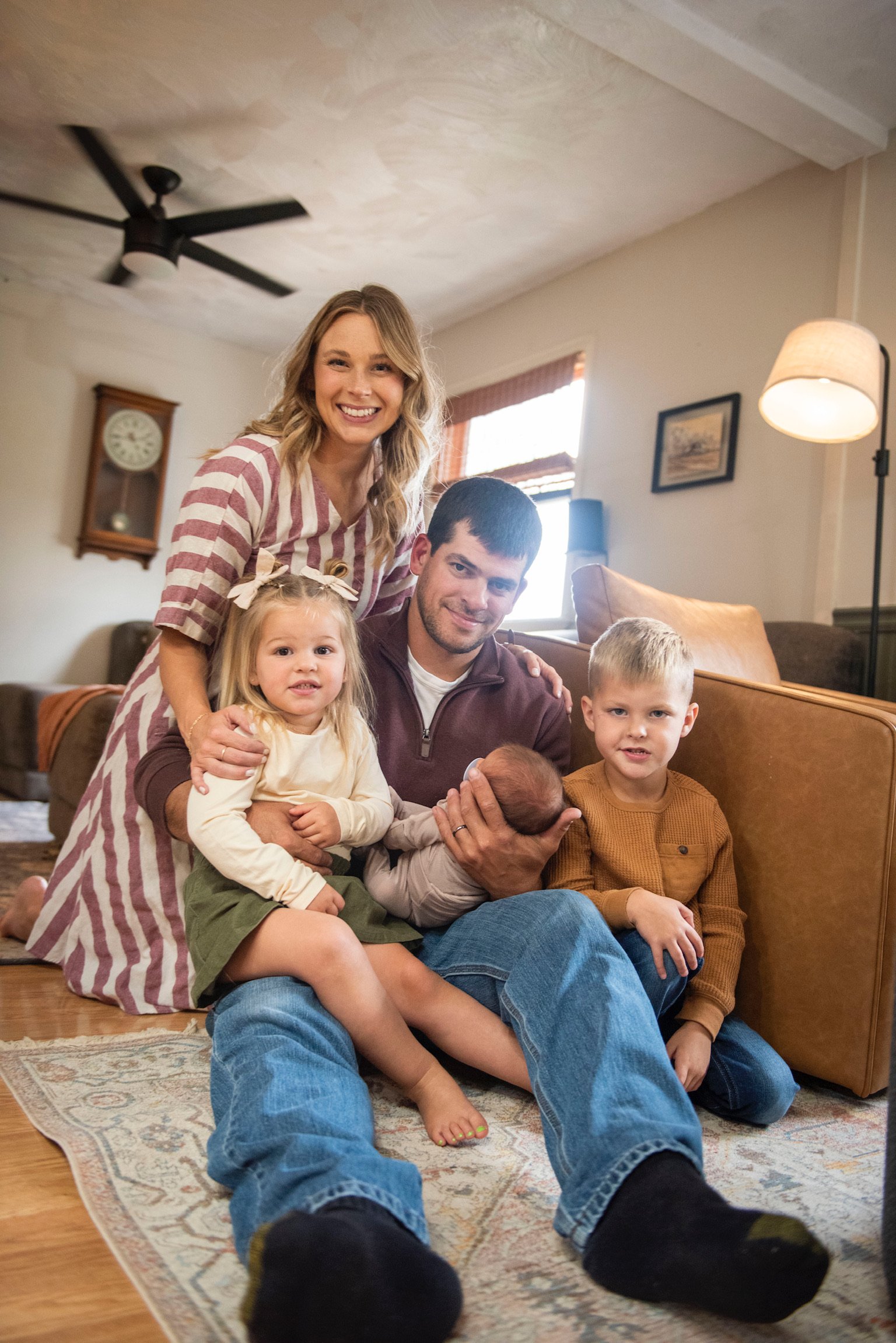 The Reitano family, sitting on the floor inside a cozy living room, smiling at the camera.