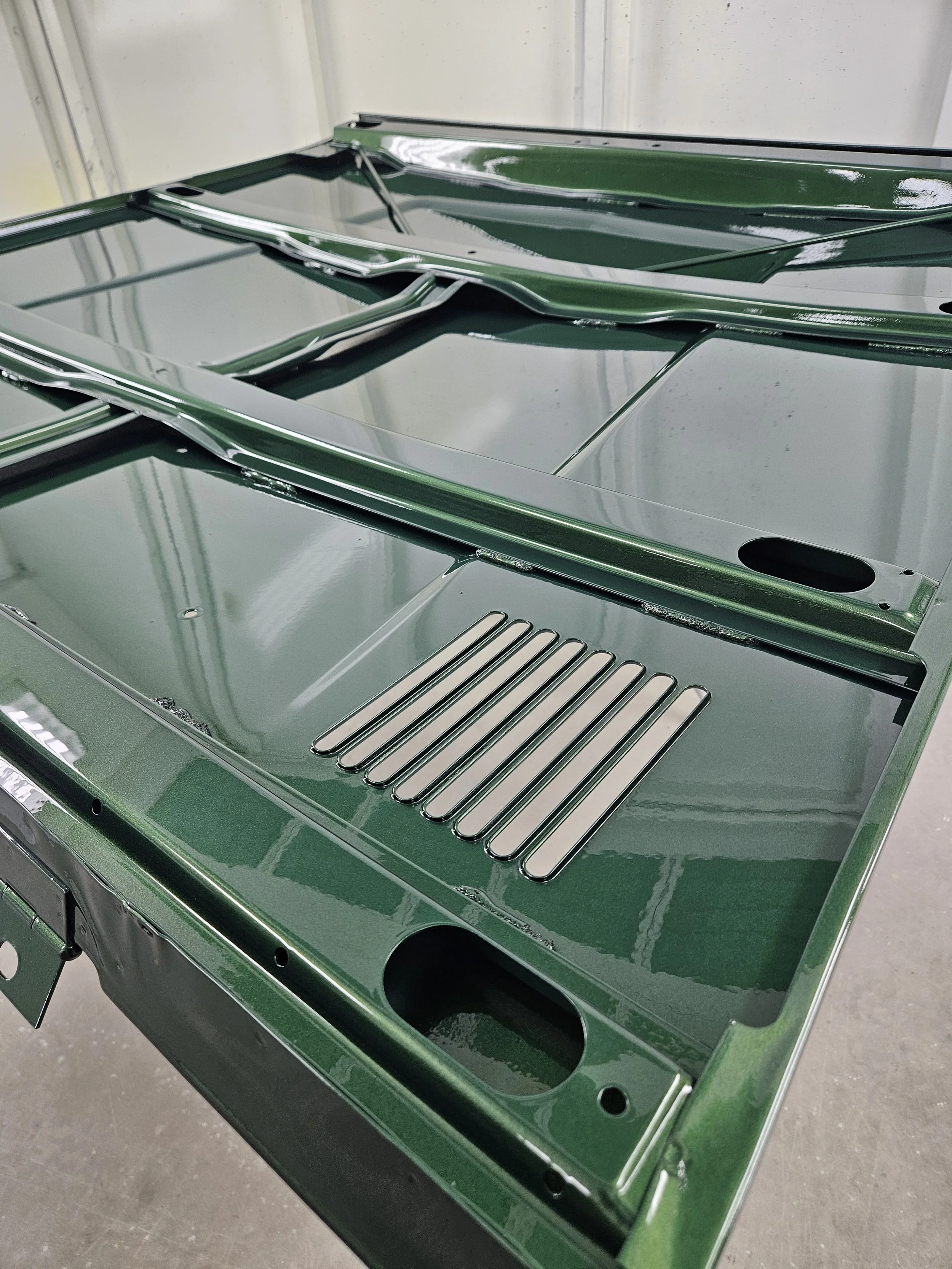 Close-up of a green painted stainless steel stove top with multiple burners and ventilation slots.