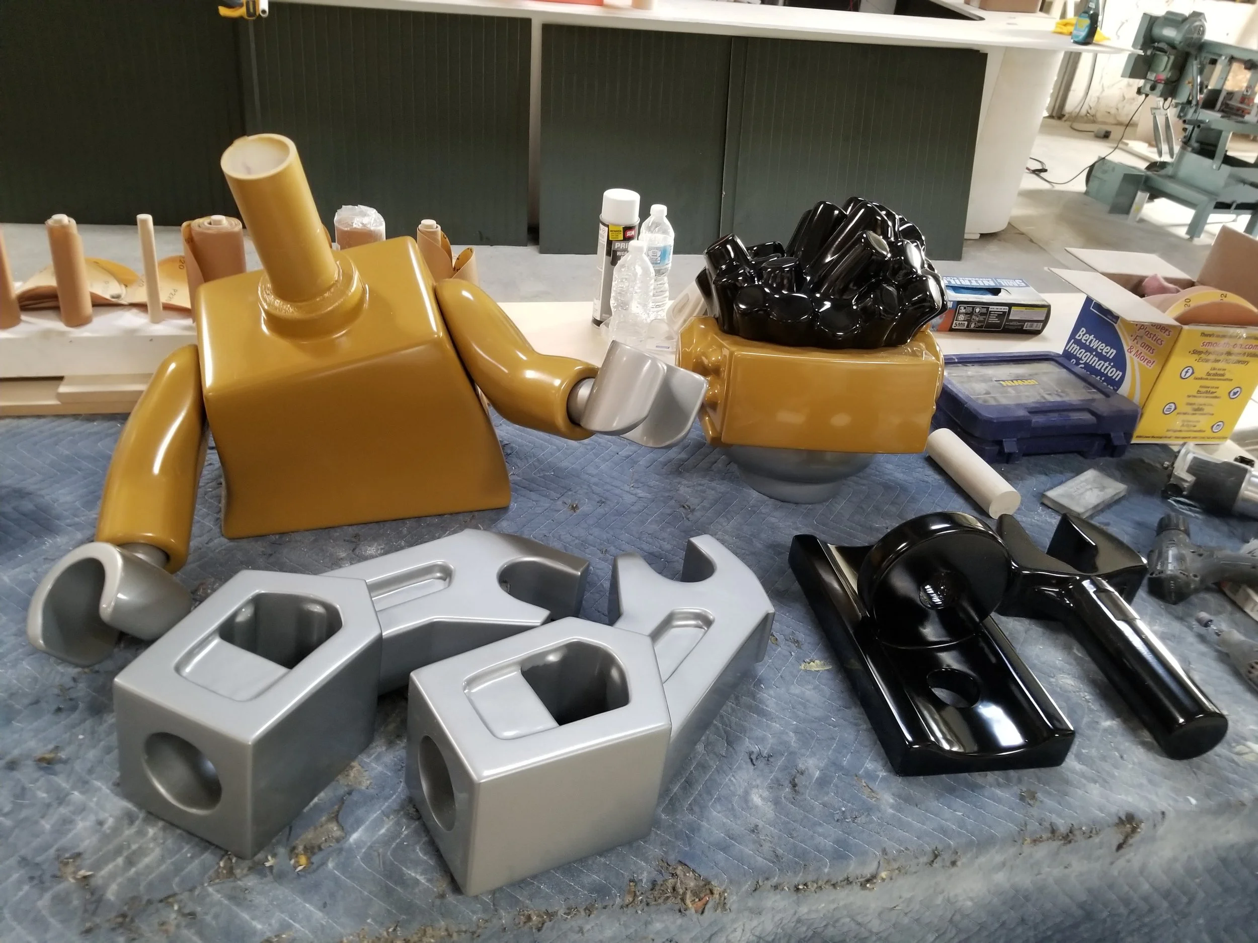 Colorful robot model and LEGO sculpture parts on a workshop table.
