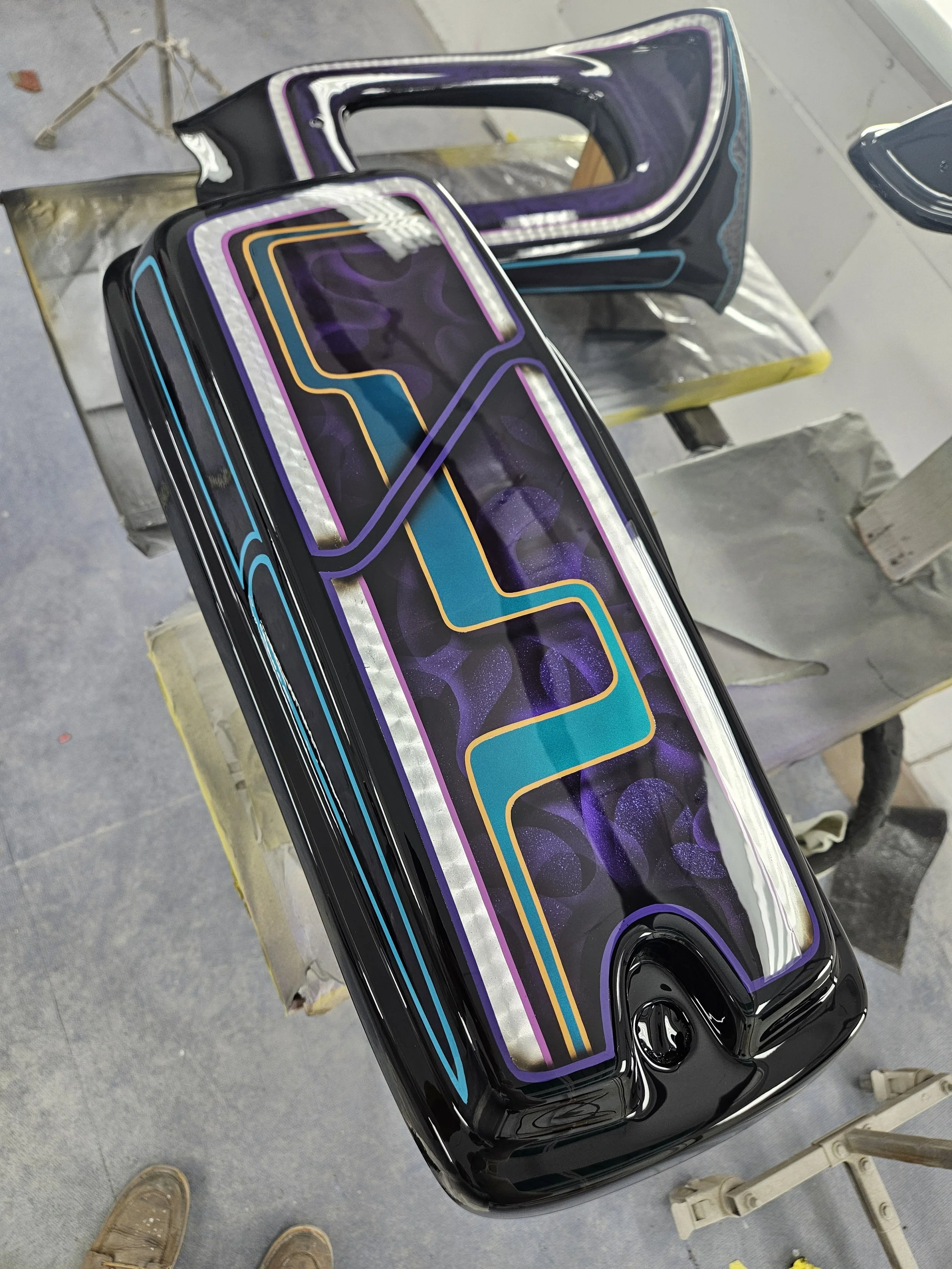 Colorful neon lights design on a black surface, possibly an art piece or decorative object, with reflections on a glossy finish.