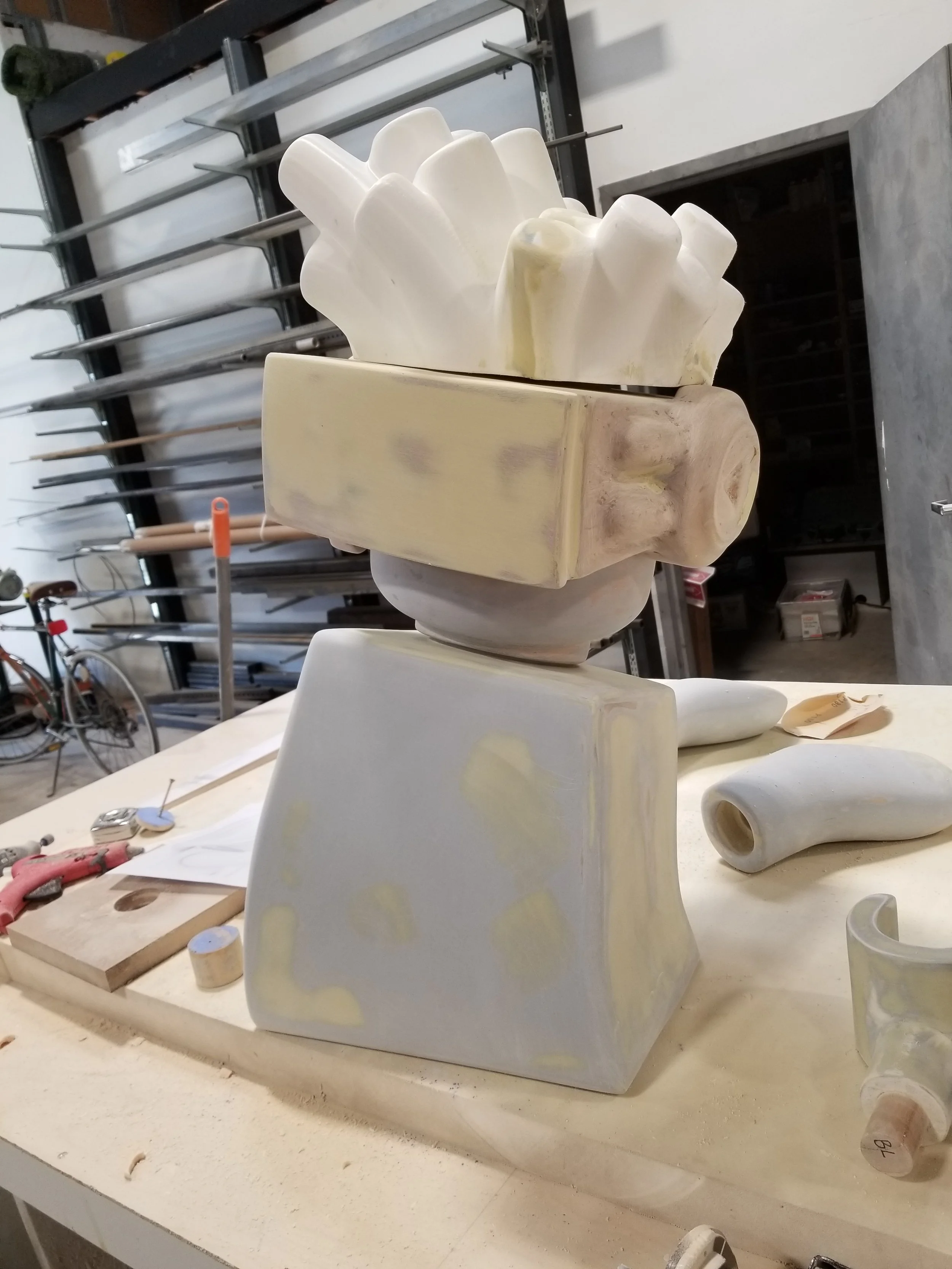 Unfinished LEGO robot sculpture on a workshop table.